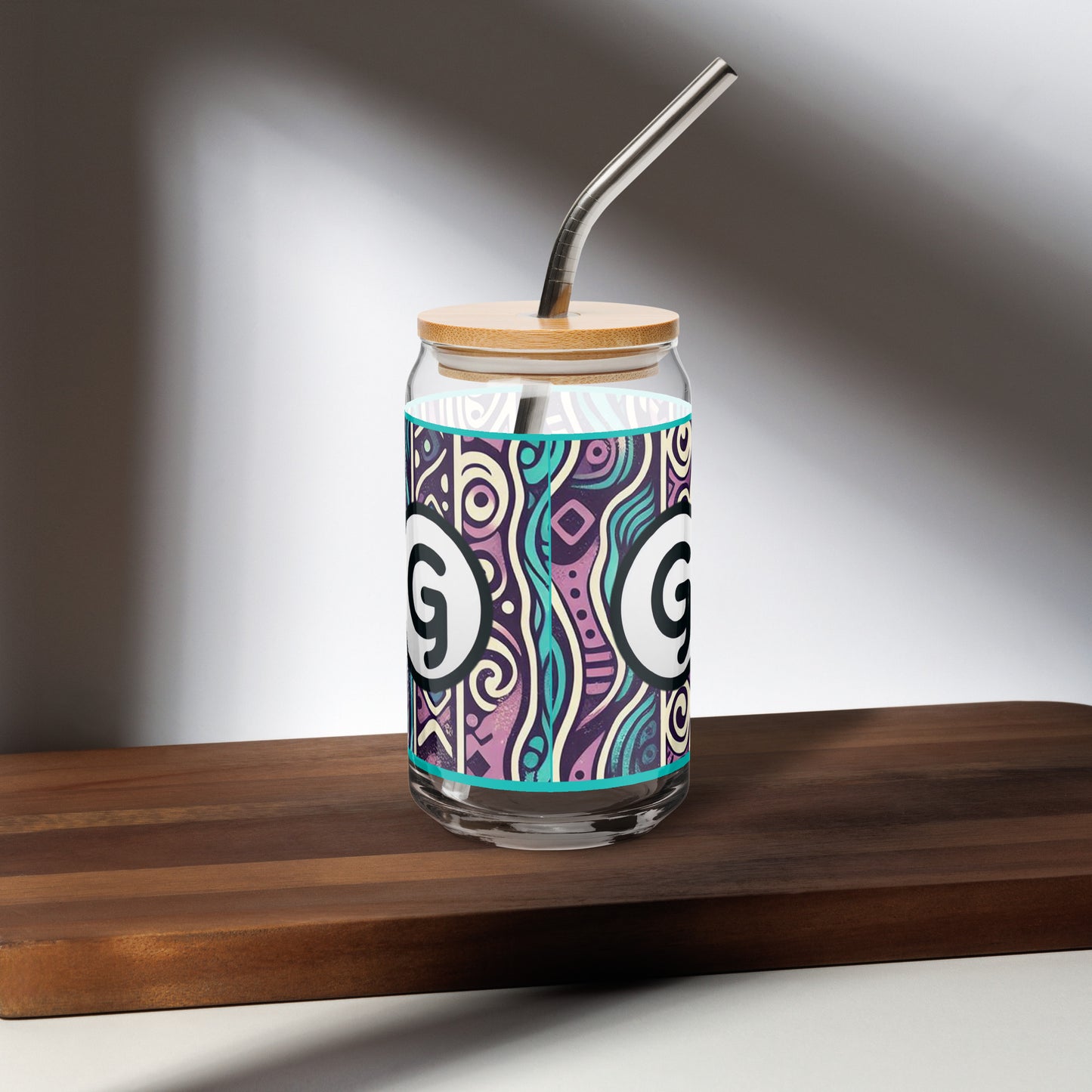 Back of can-shaped glassware with 'g' girlish logo on teal, purple, black, and white patterned background