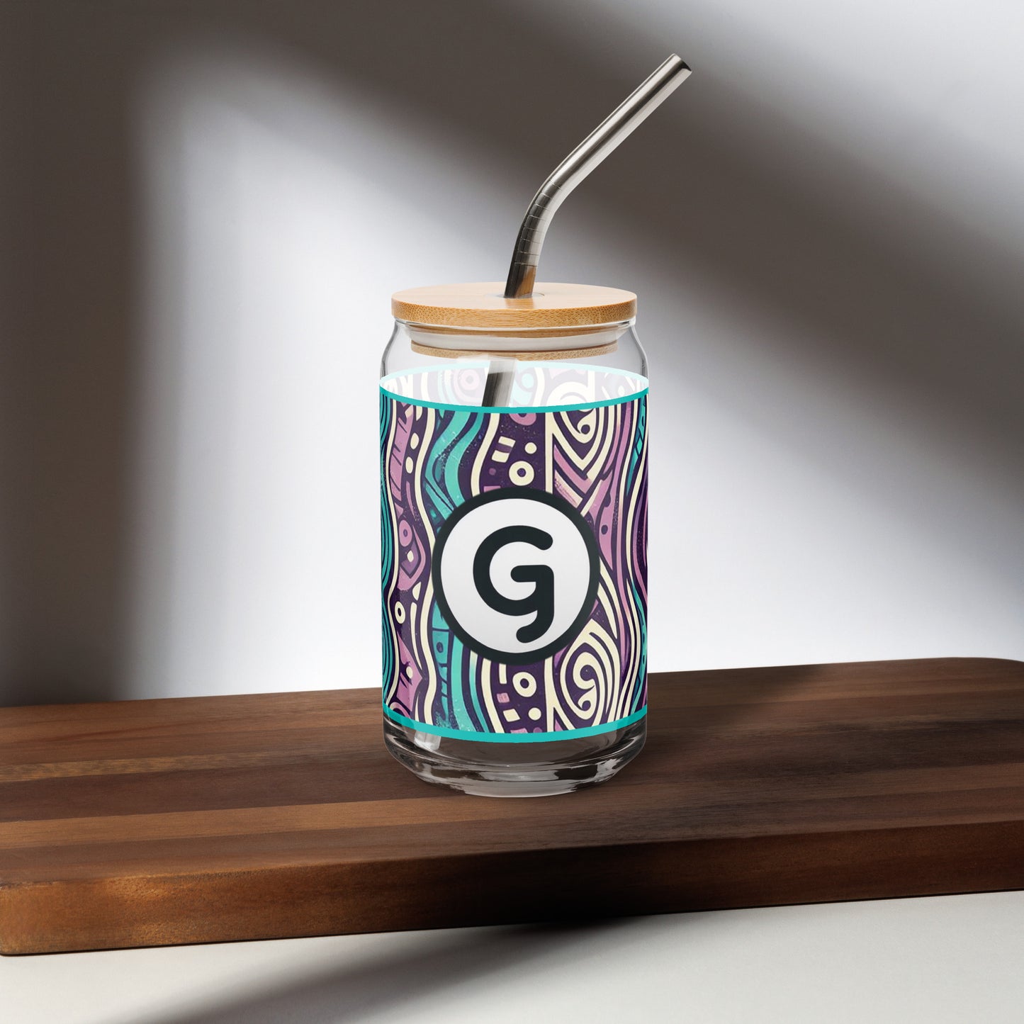 Front of can-shaped glassware with 'g' girlish logo on teal, purple, black, and white patterned background