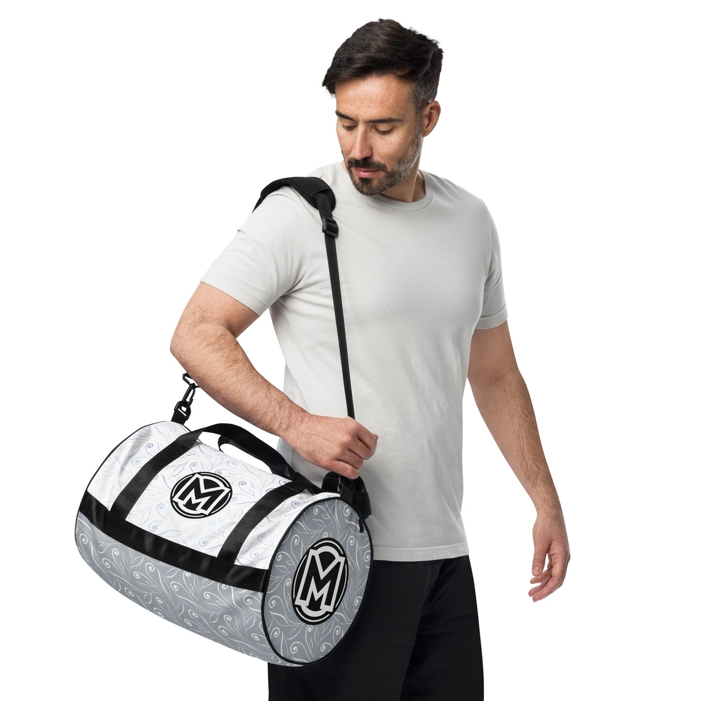 Left front of light blue gym bag with blue swirl background and 'M' logos being carried by a man