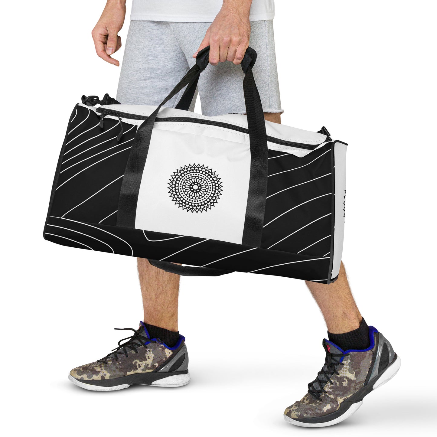 Front of black and white print duffle bag with black mandala being carried by male