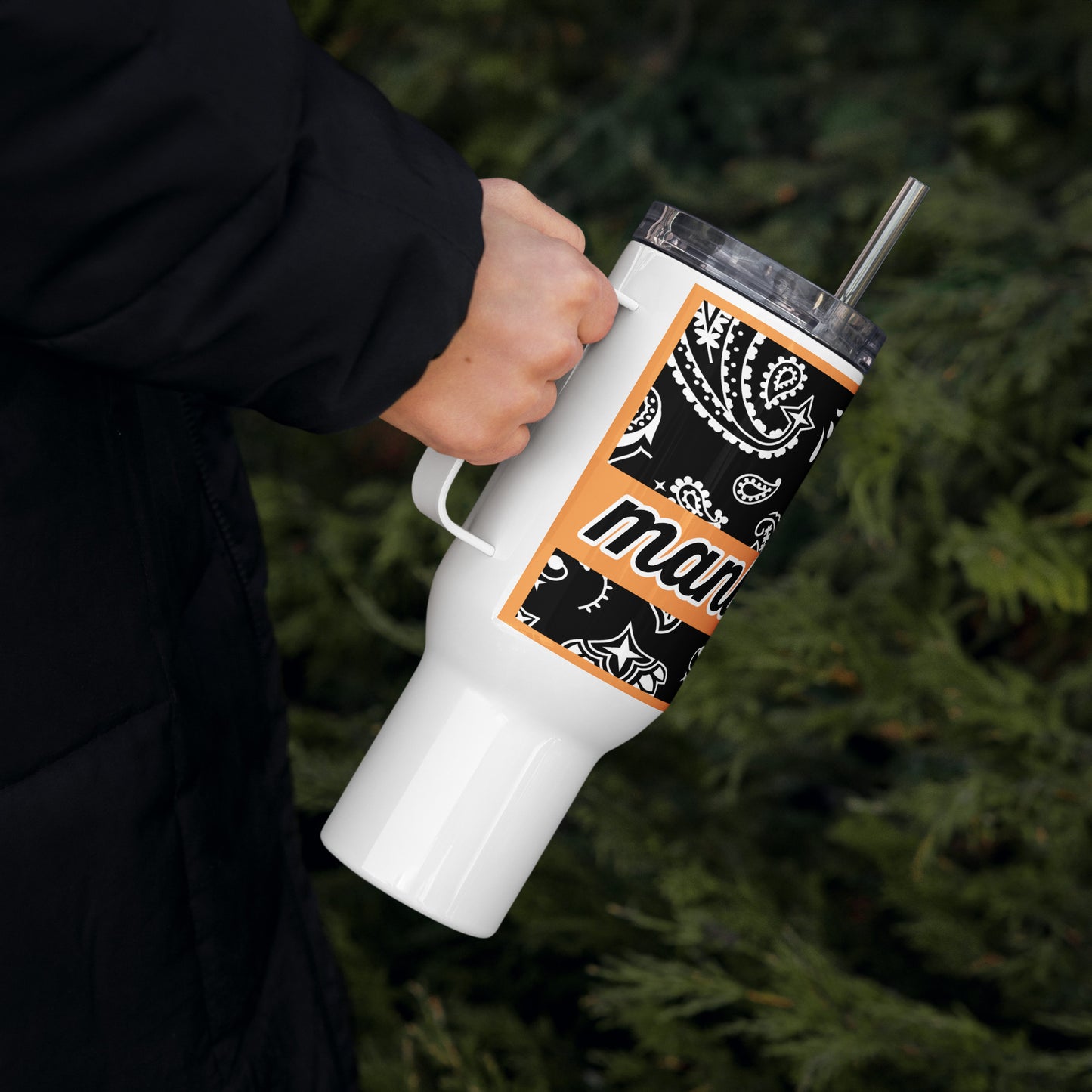 Right of travel mug with black and white paisley and word 'manly' on top of orange banner being held