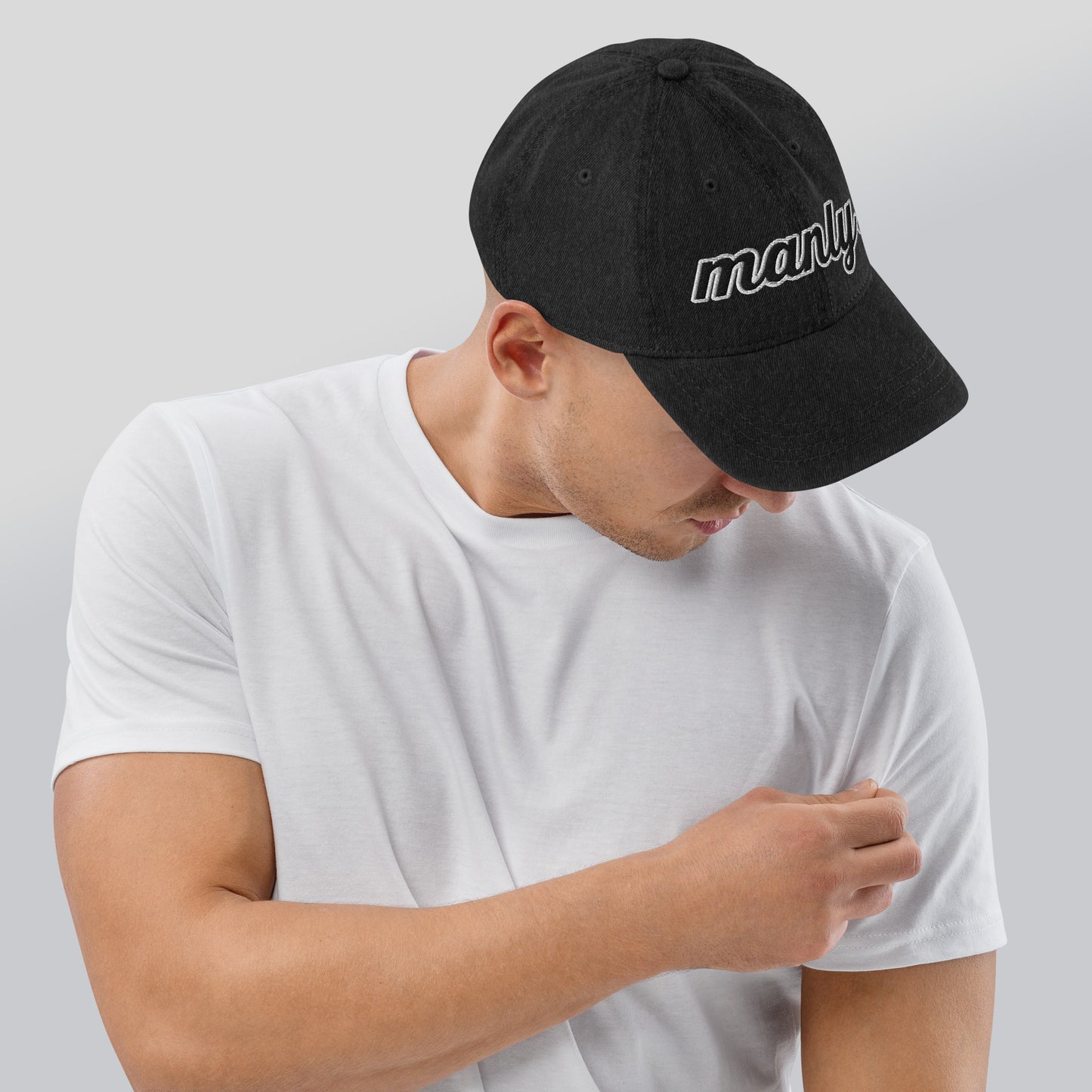 Right of black cotton hat with words 'manly' embroidered across the front