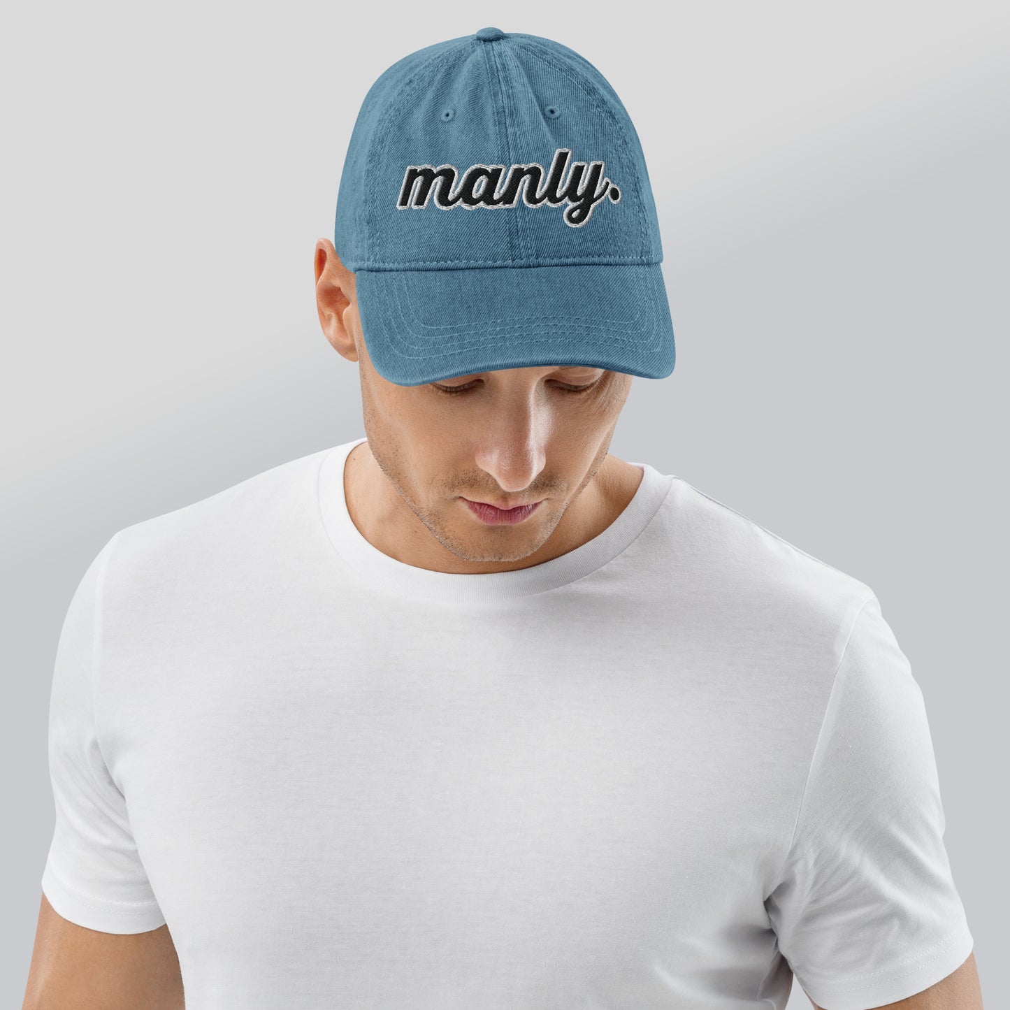 Front of blue cotton hat with words 'manly' embroidered across the front