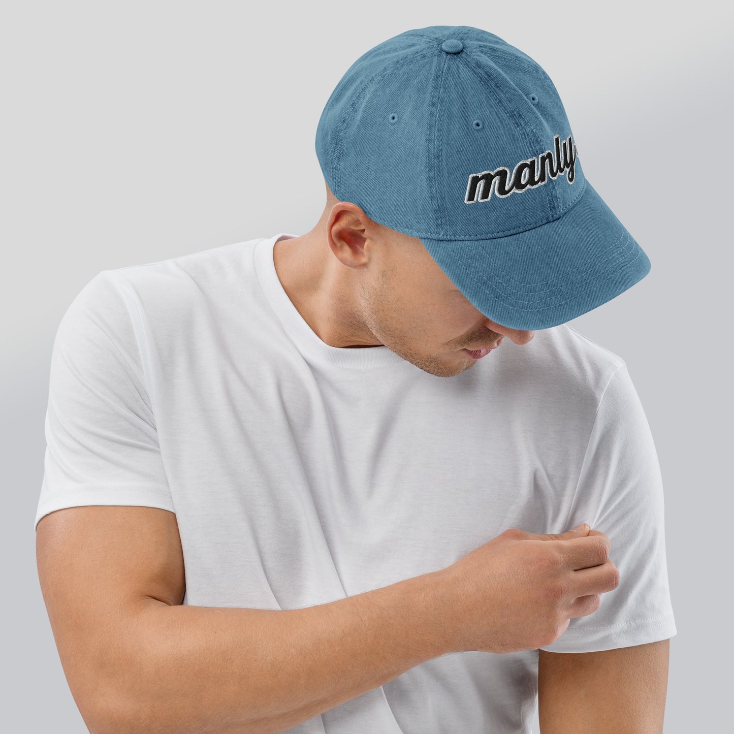 Right of blue cotton hat with words 'manly' embroidered across the front