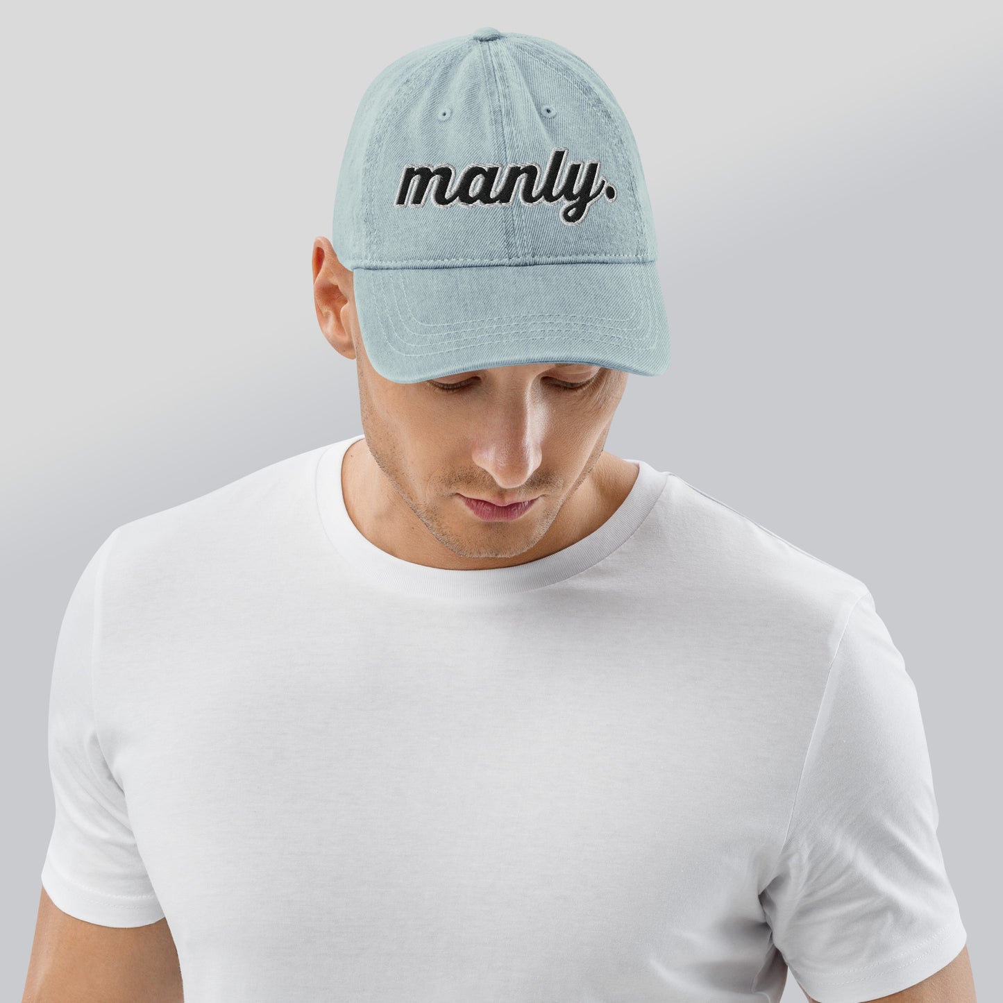 Front of light blue cotton hat with words 'manly' embroidered across the front