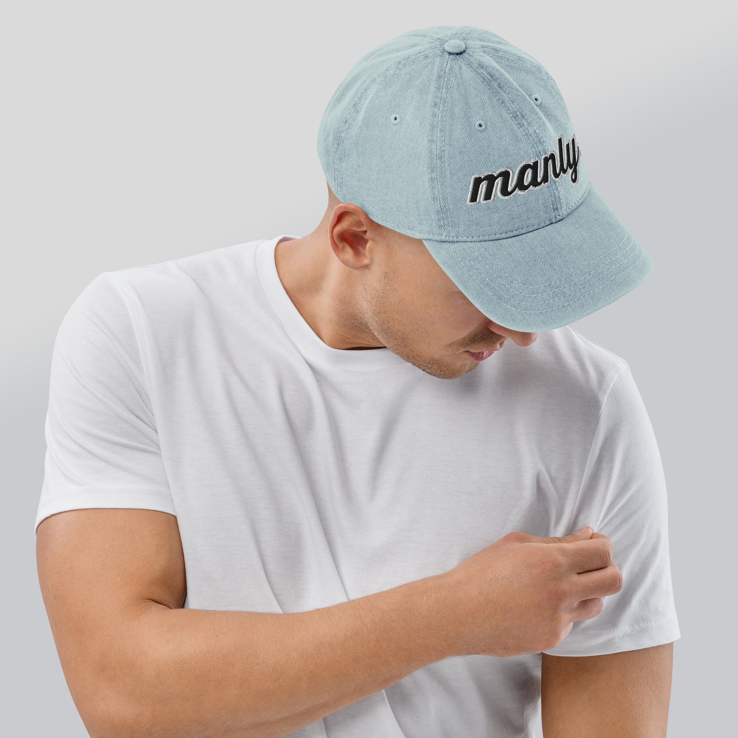 Right of light blue cotton hat with words 'manly' embroidered across the front