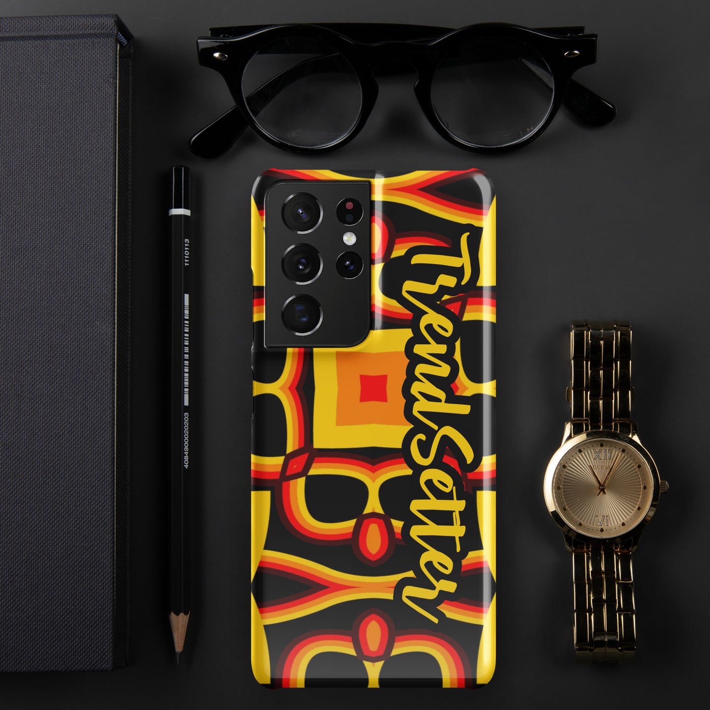 Front of gold, yellow, red and black print Samsung s21 glossy case with text "TrendSetter' in black and gold