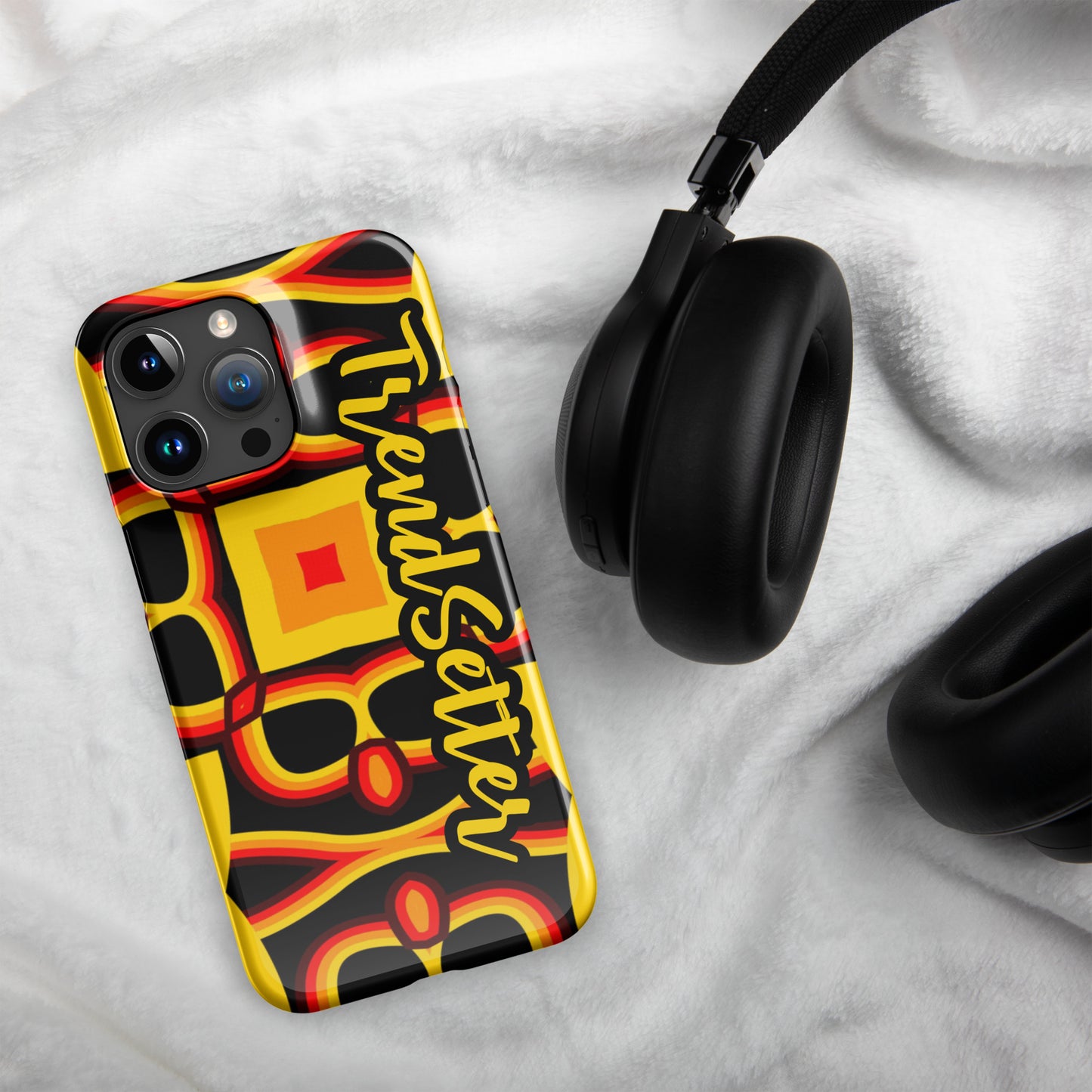 Front of gold, yellow, red and black print iPhone 15 glossy case with text "TrendSetter' in black and gold