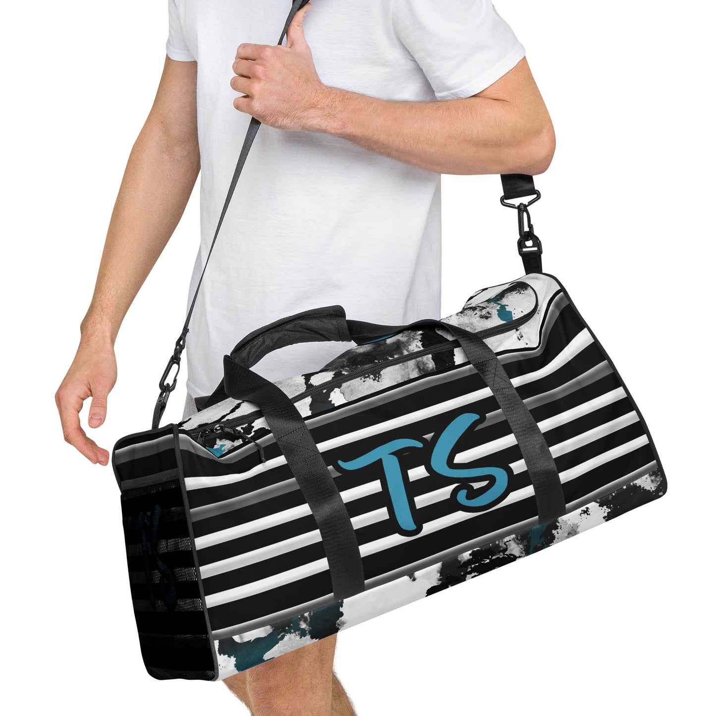Right front of man holding black, white and blue stripped and patterned duffel with 'TS' text in blue