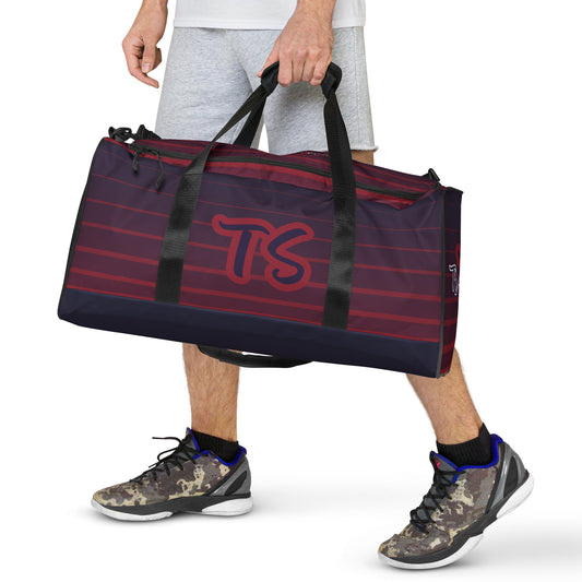 Front of TrendSetter United Duffle Bag being carried by a man and with red and blue stripped design and with TS logo