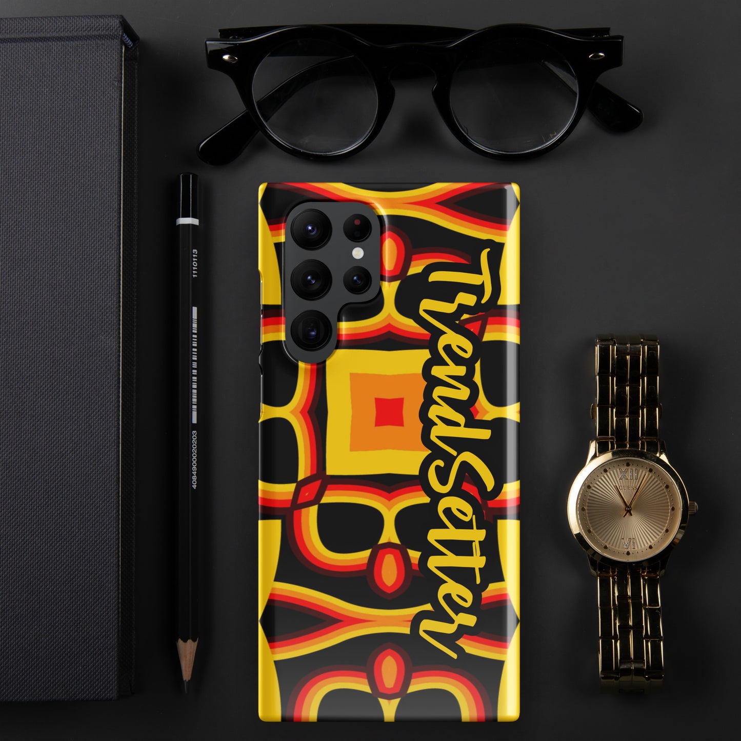 Front of gold, yellow, red and black print Samsung s22 glossy case with text "TrendSetter' in black and gold