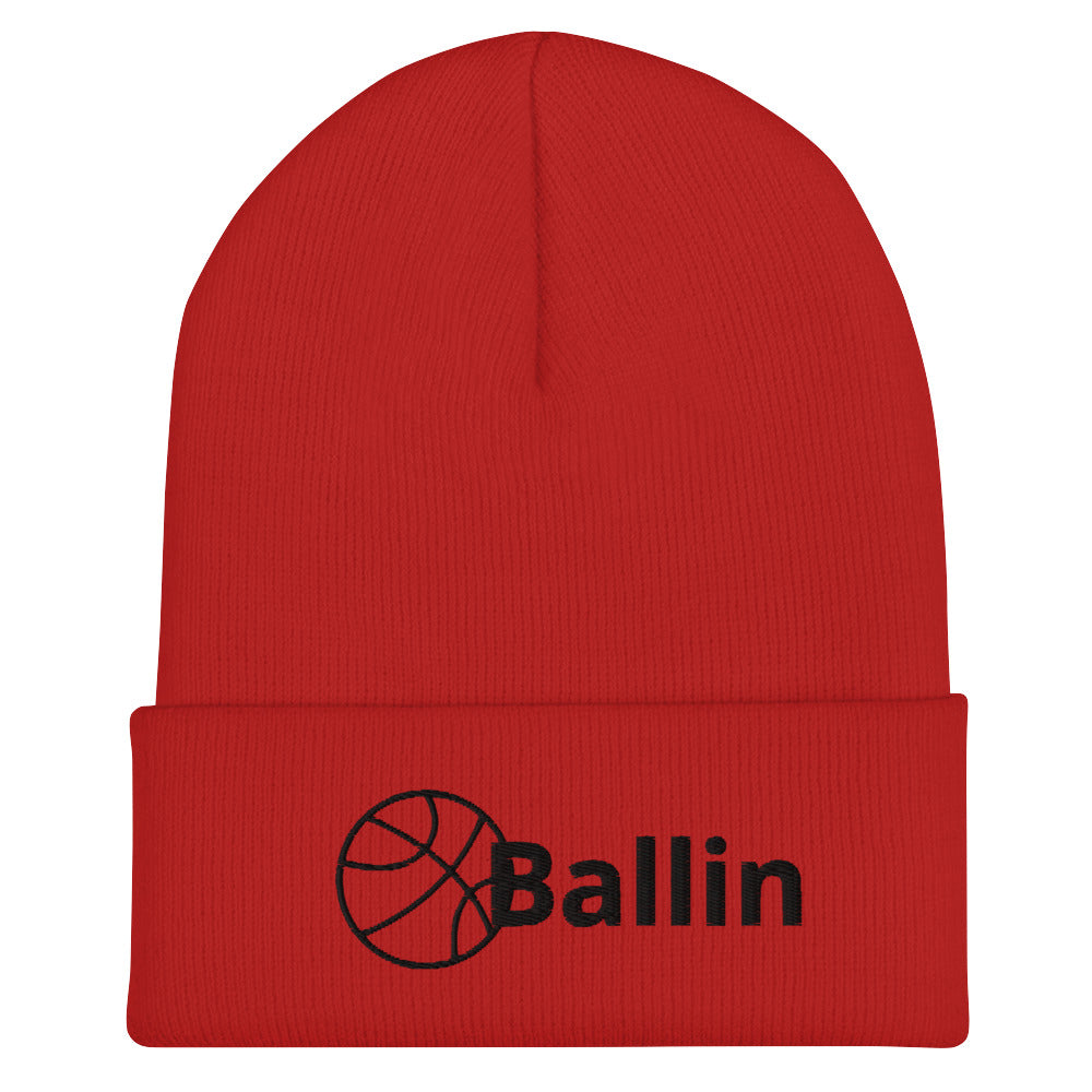 Front of red cuffed beanie with black logo of basketball and word saying 'ballin'