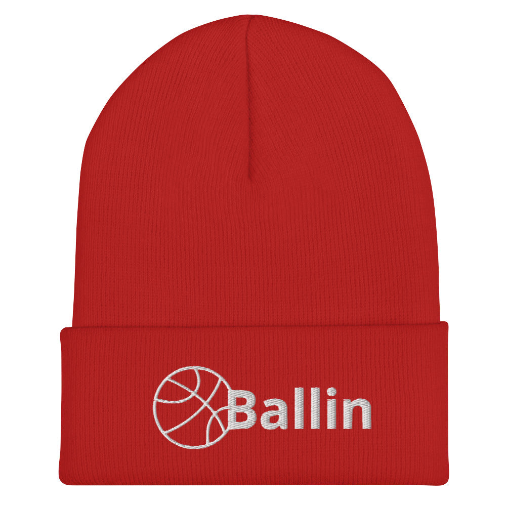 Front of red cuffed beanie with white logo of basketball and word saying 'ballin'