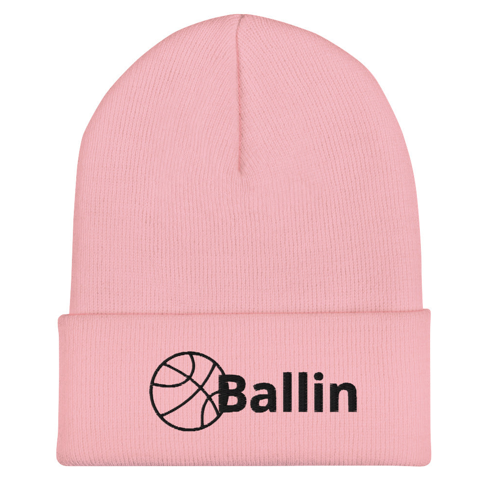 Front of pink cuffed beanie with black logo of basketball and word saying 'ballin'