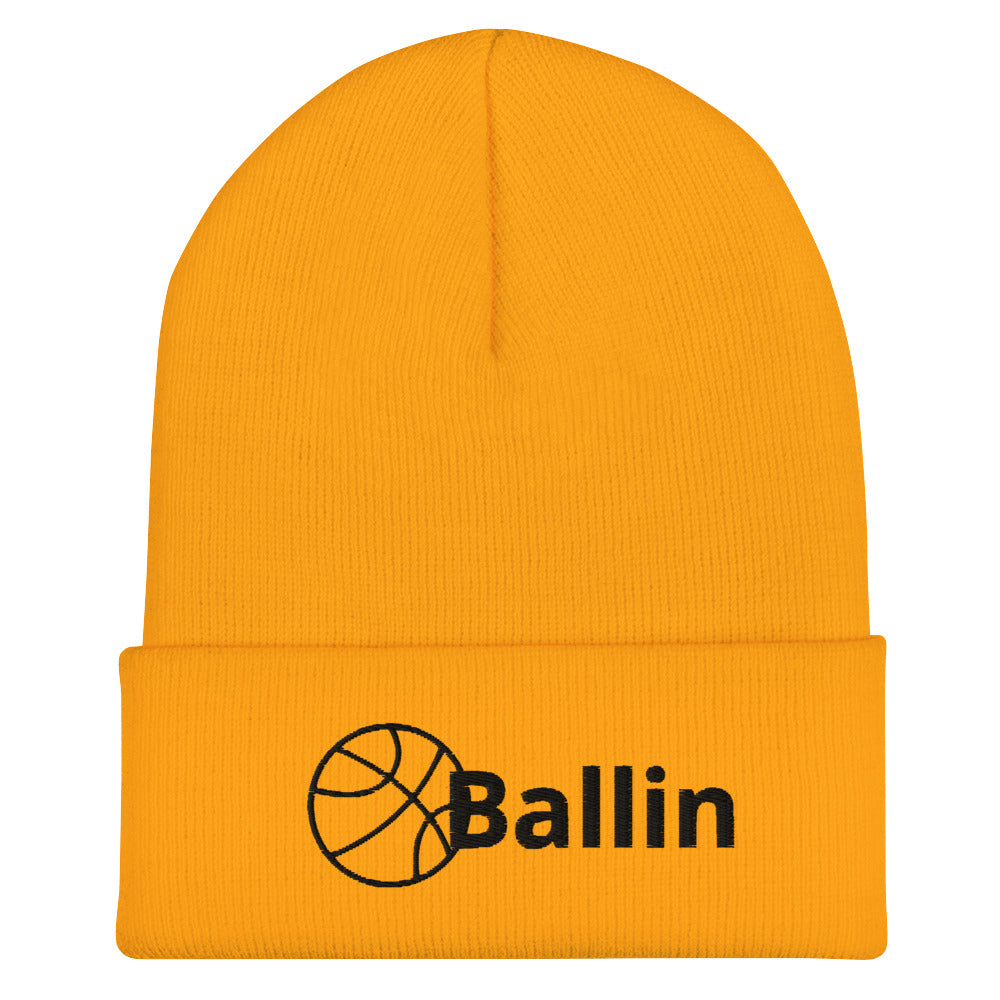 Front of gold cuffed beanie with black logo of basketball and word saying 'ballin'