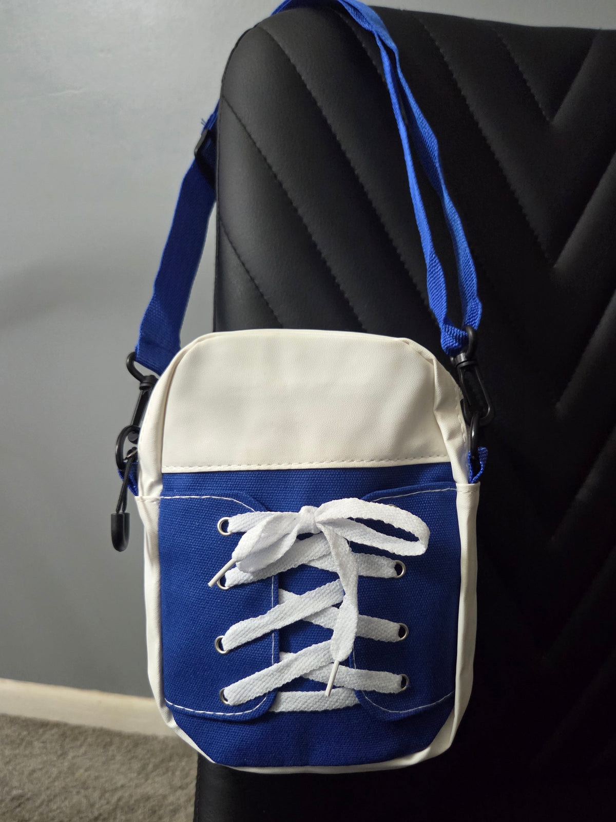 Back view of Blue and White Sneaker Shoulder Bag in faux leather and cloth blend fabrics, featuring a blue strap, resting on a black leather chair. Close up view.