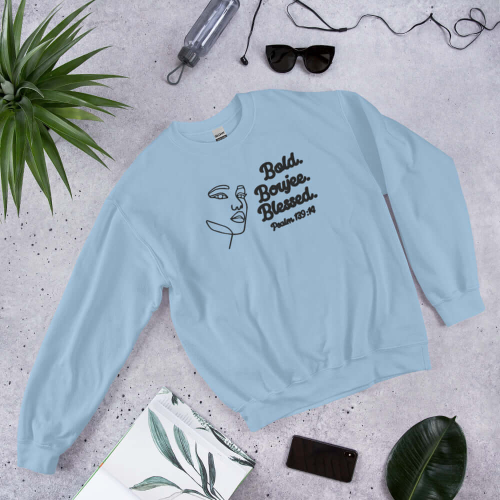 Front of light blue sweatshirt with outline of a woman's face in black and text saying 'Bold, Boujee, Blessed and Psalm 139:14' in black