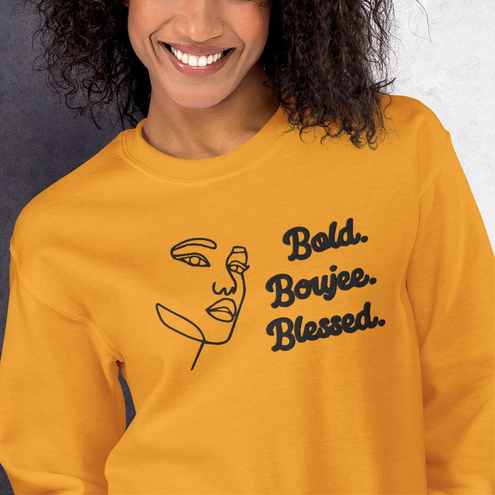 Zoomed gold sweatshirt with outline of a woman's face and text saying 'Bold, Boujee, Blessed' in black