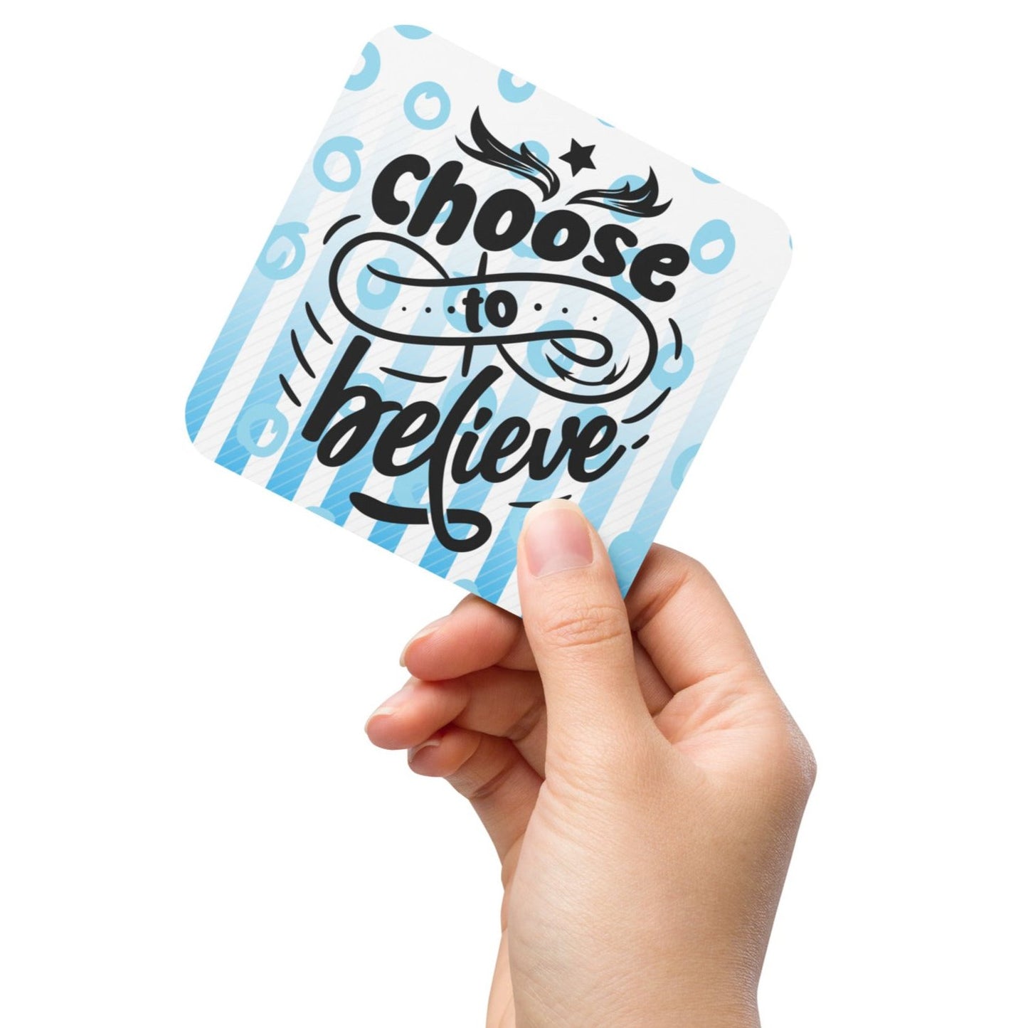 Cork-back-coaster with blue and white lines and circles on the background and text saying 'choose to believe'