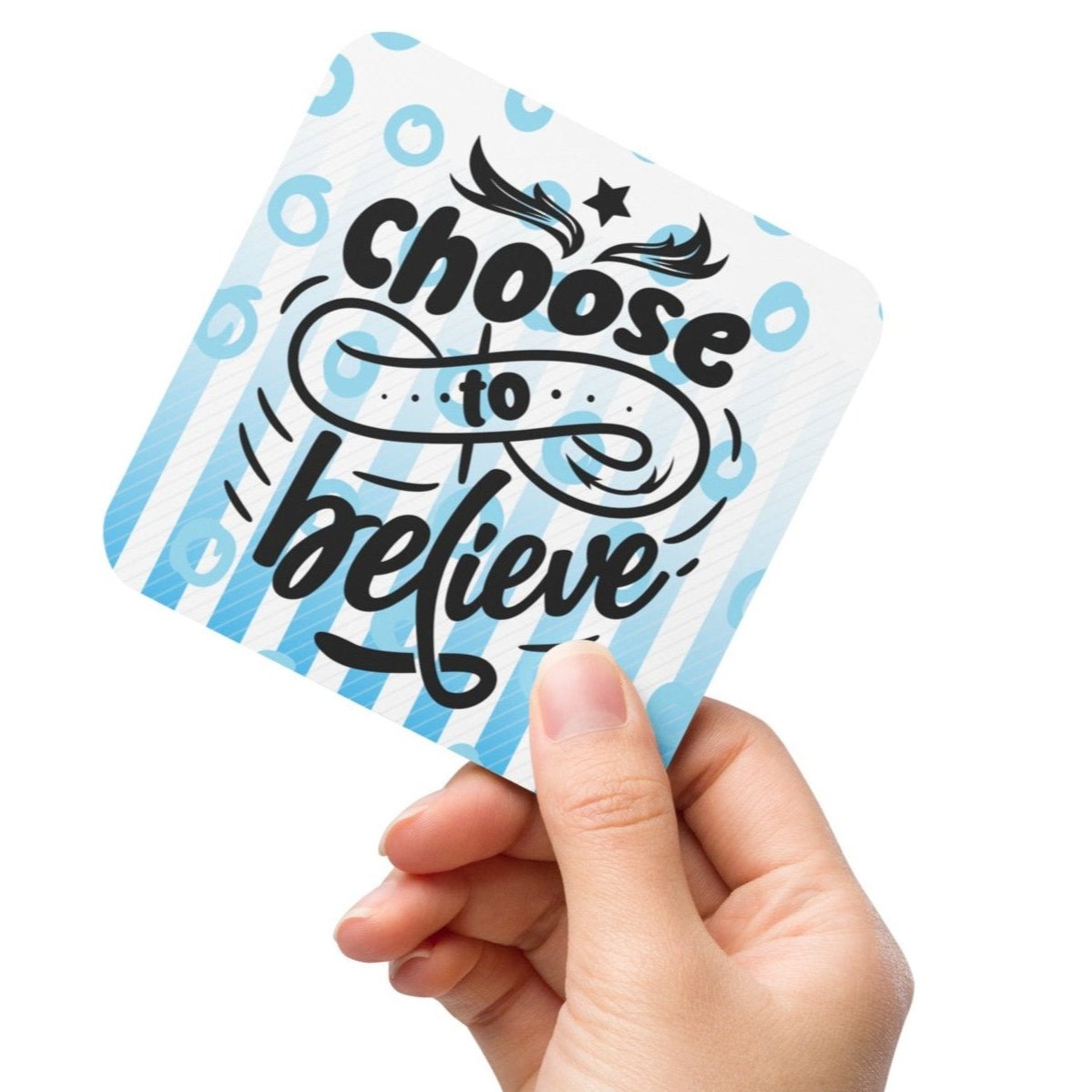 Cork-back-coaster with blue and white lines and circles on the background and text saying 'choose to believe'