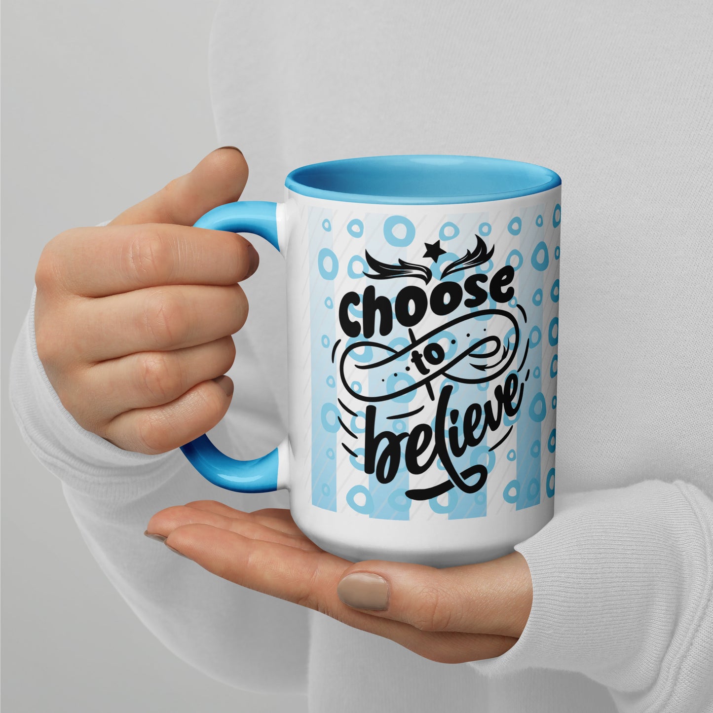 Left view of a 15 oz mug with light blue inside, outside is light blue lines and circle background, and black text saying 'choose to believe'