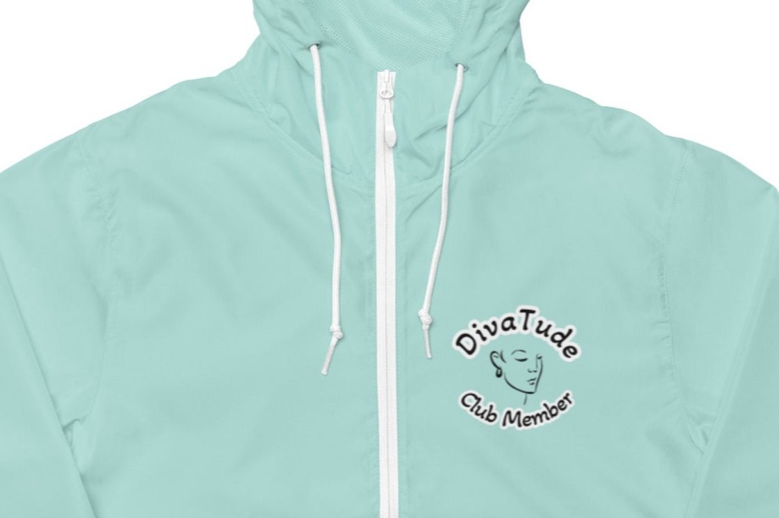 Front of women's aqua windbreaker with image on top left of embroidered lady's face in black with grey and black text saying "DivaTude' above and 'Club Member' below 