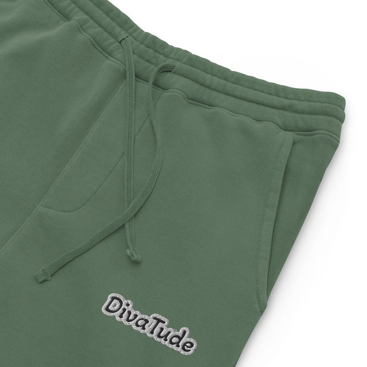 Front, left top of alpine green sweatpants with black embroidered text reading 'DivaTude' at top thigh of pant