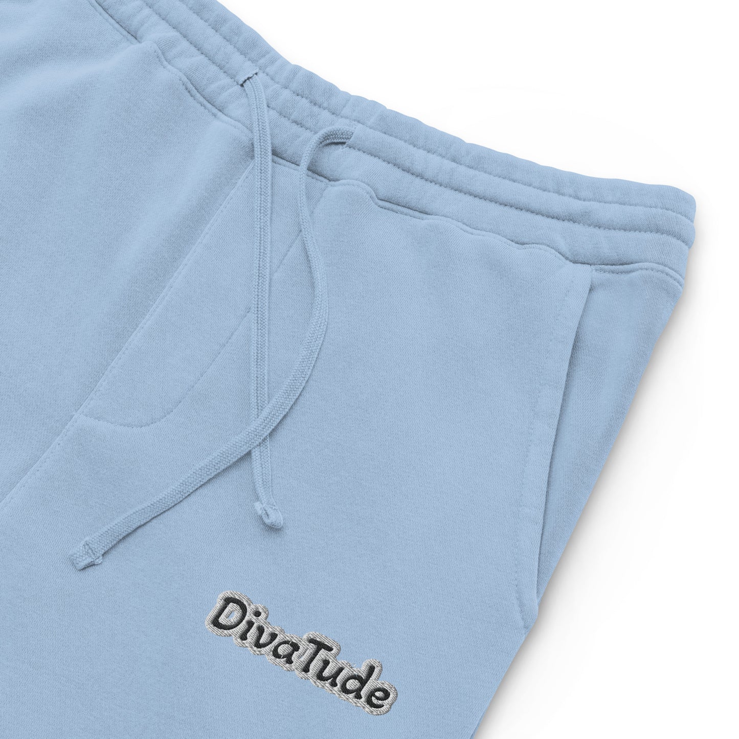 Front, left top of light blue sweatpants with black embroidered text reading 'DivaTude' at top thigh of pant