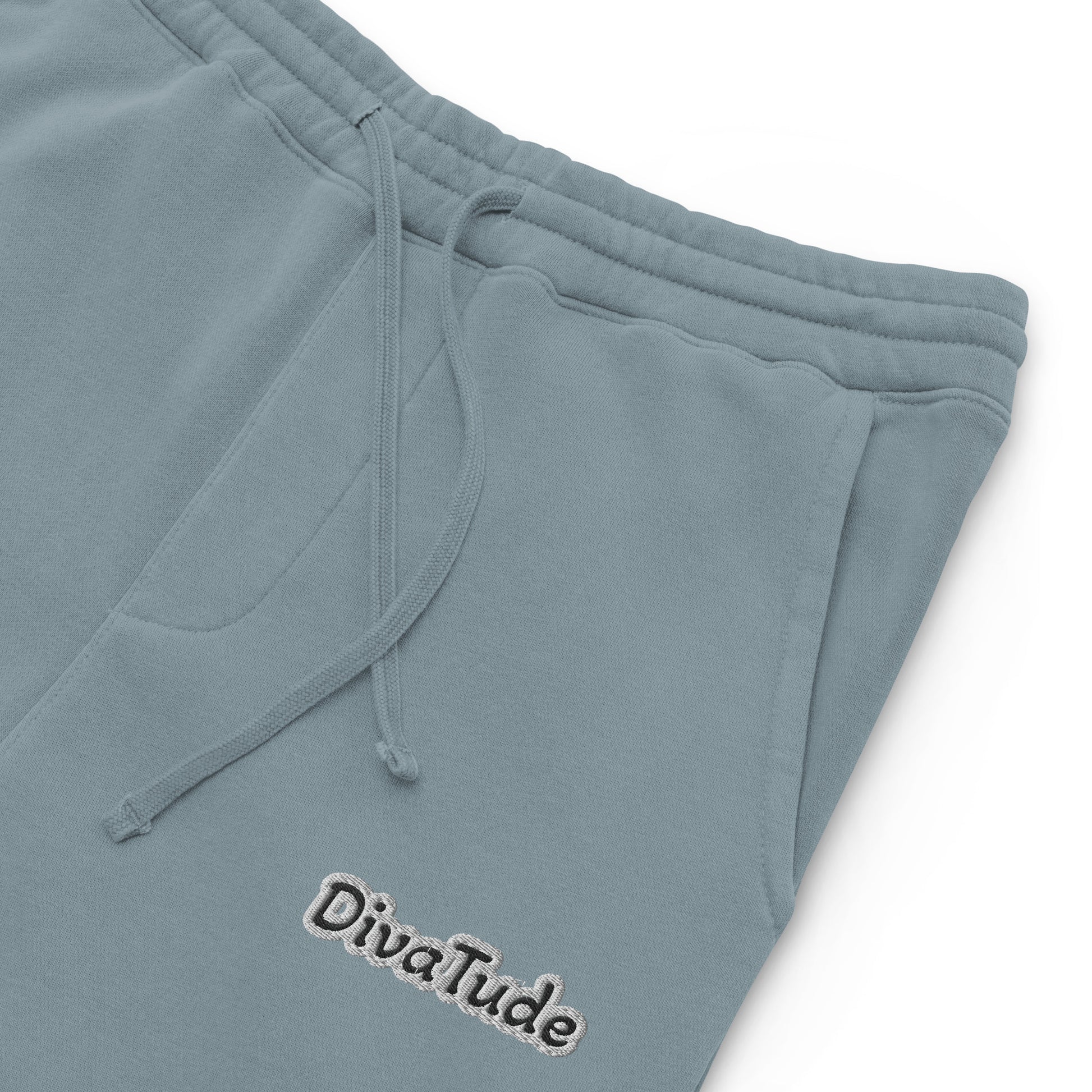 Front, left top of slate blue sweatpants with black embroidered text reading 'DivaTude' at top thigh of pant