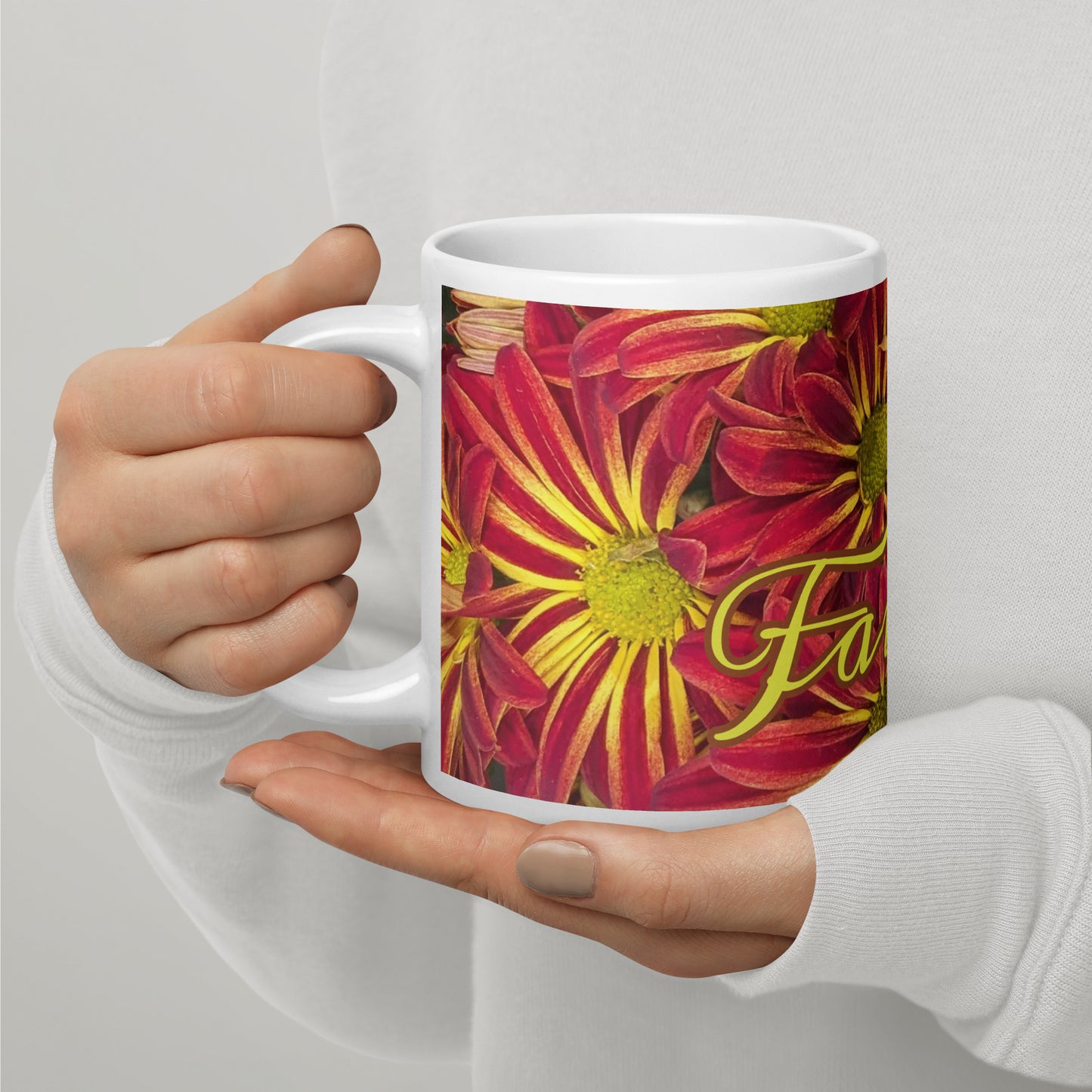 Left view of a white glossy mug with   fuchsia and yellow flowered background and partial of front view text saying 'faithful'