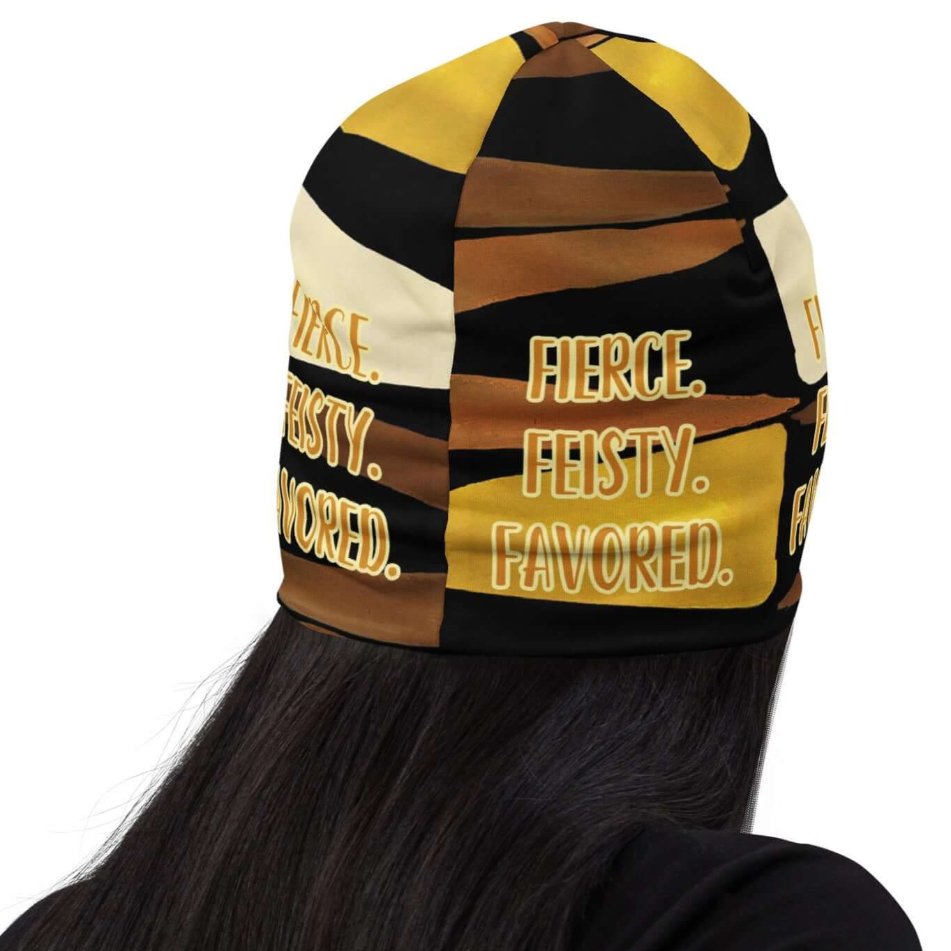 Back head shot of woman wearing a black, brown, beige and gold print beanie with gold and white text saying 'Fierce.Feisty.Favored.'