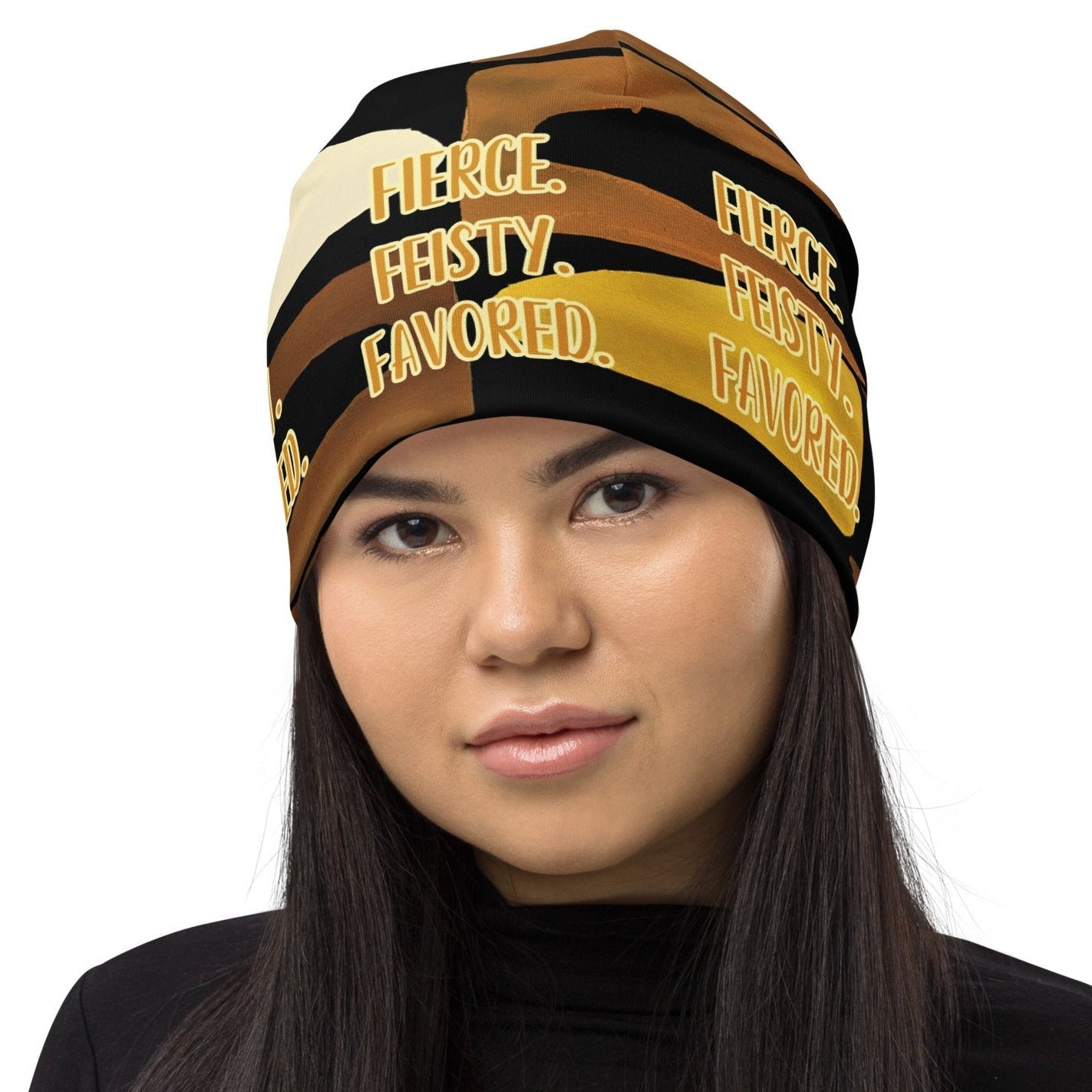 Front head shot of woman wearing a black, brown, beige and gold print beanie with gold and white text saying 'Fierce.Feisty.Favored.'