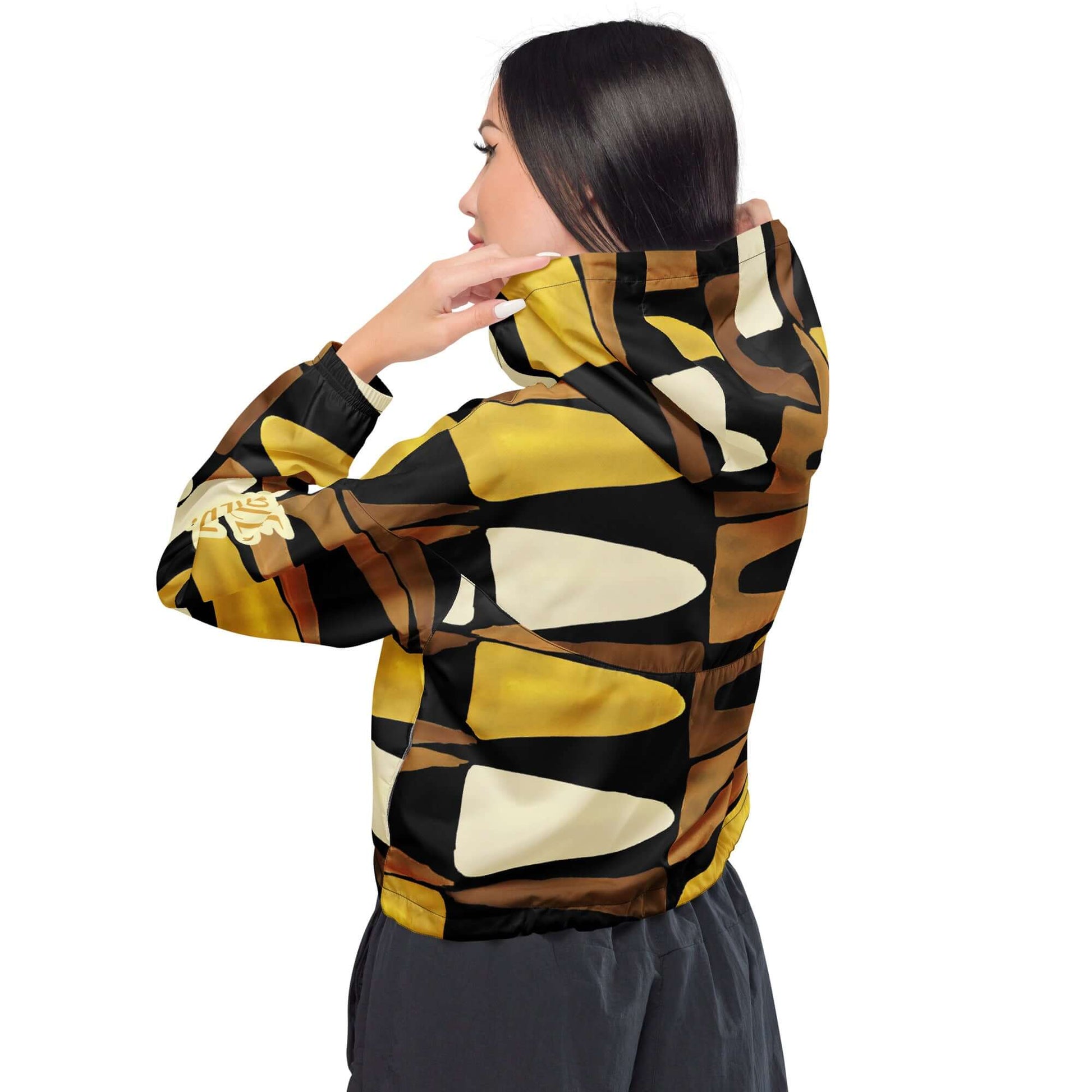 Back view of a cropped black, brown, beige and gold print windbreaker with gold and white text saying 'Fierce.Feisty.Favored.' on the left sleeve