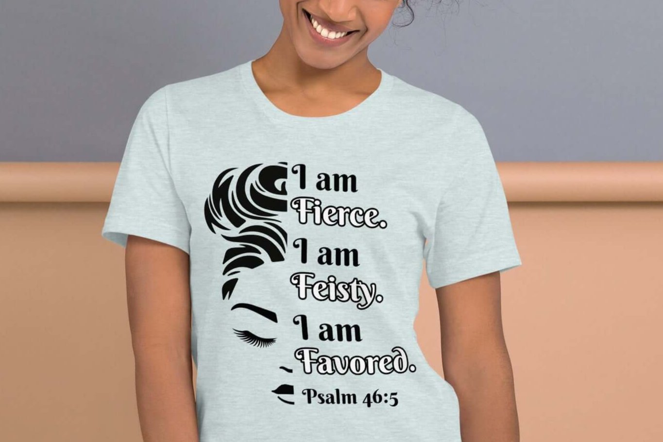 Front of ice blue t-shirt with image of half woman's face with black and white text saying "I am fierce, I am feisty, I am favored and Psalm 46:3'