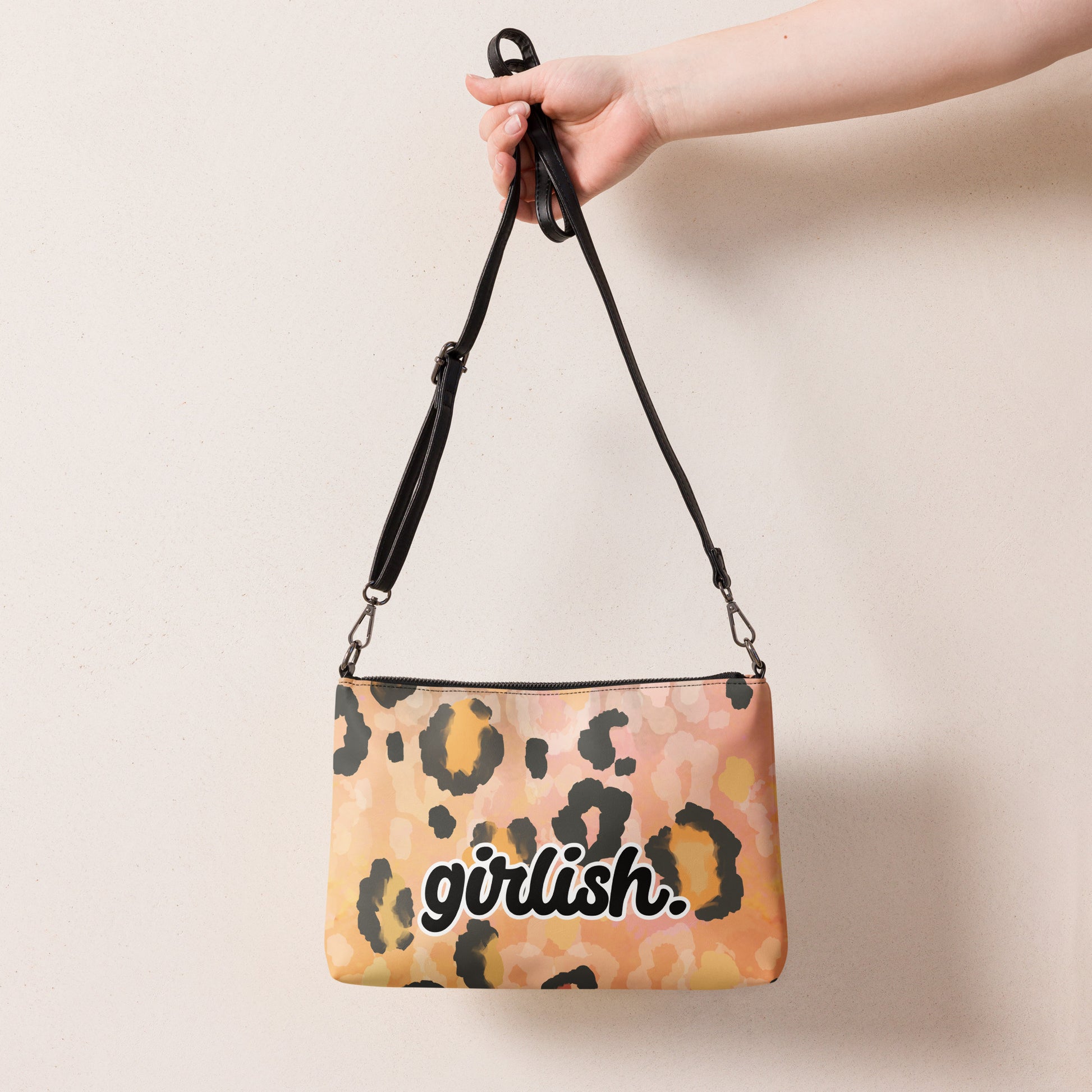 Back of Girlish cheetah print peach crossbody bag being held by strap and with text "girlish" on near bottom