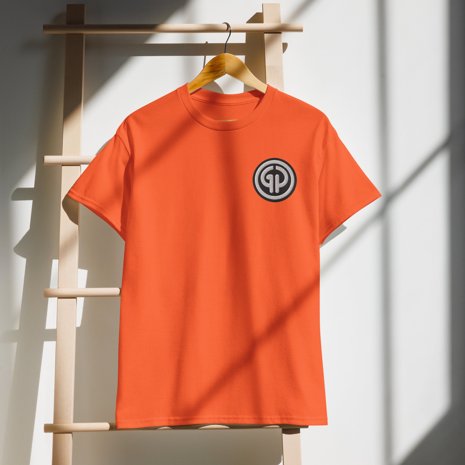 Front of hanging orange t-shirt with God's Property 'GP' emblem embroidered on left chest