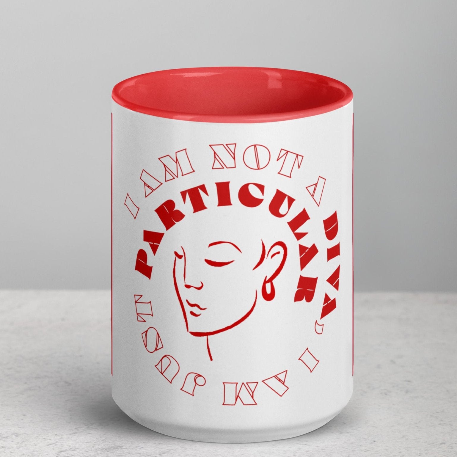 Front view of white mug with red inside and a red outline of woman's face circled by red and white text saying 'I am not a Diva, I am just particular