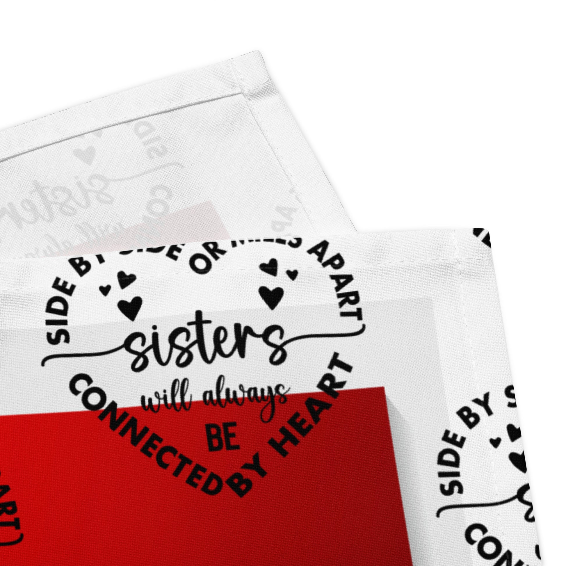 Corner detail of red and white Sisters LIWI cloth with icon saying 'Sisters will always be'