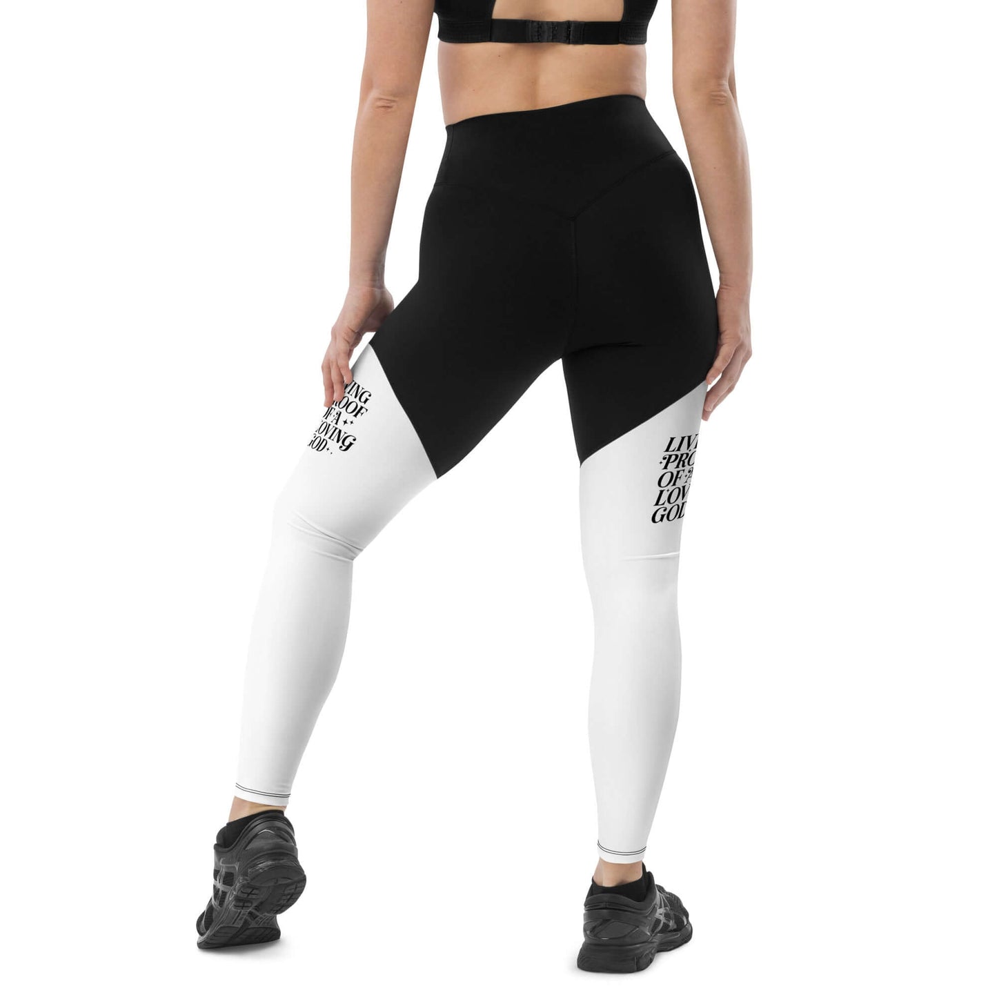 Back of black and white leggings with black text saying 'Living proof of a loving god' on both thighs