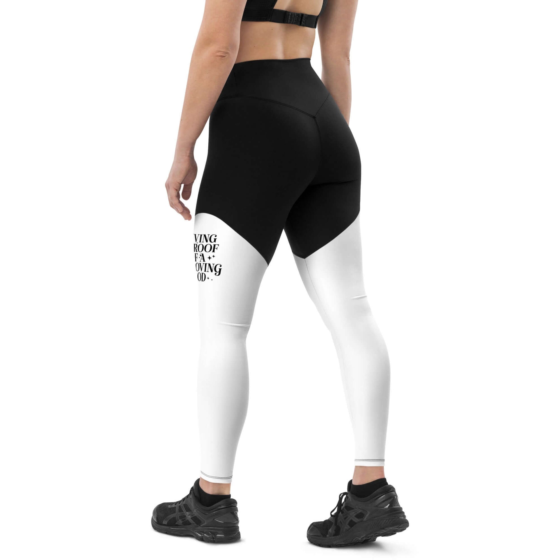 Left back of black and white leggings with black text saying 'Living proof of a loving god' on left thigh