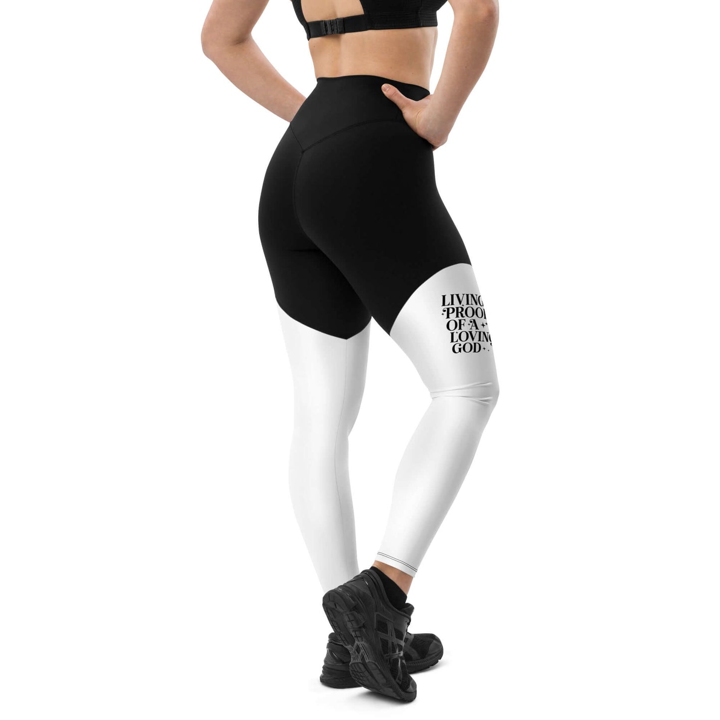 Right back of black and white leggings with black text saying 'Living proof of a loving god' on right thigh