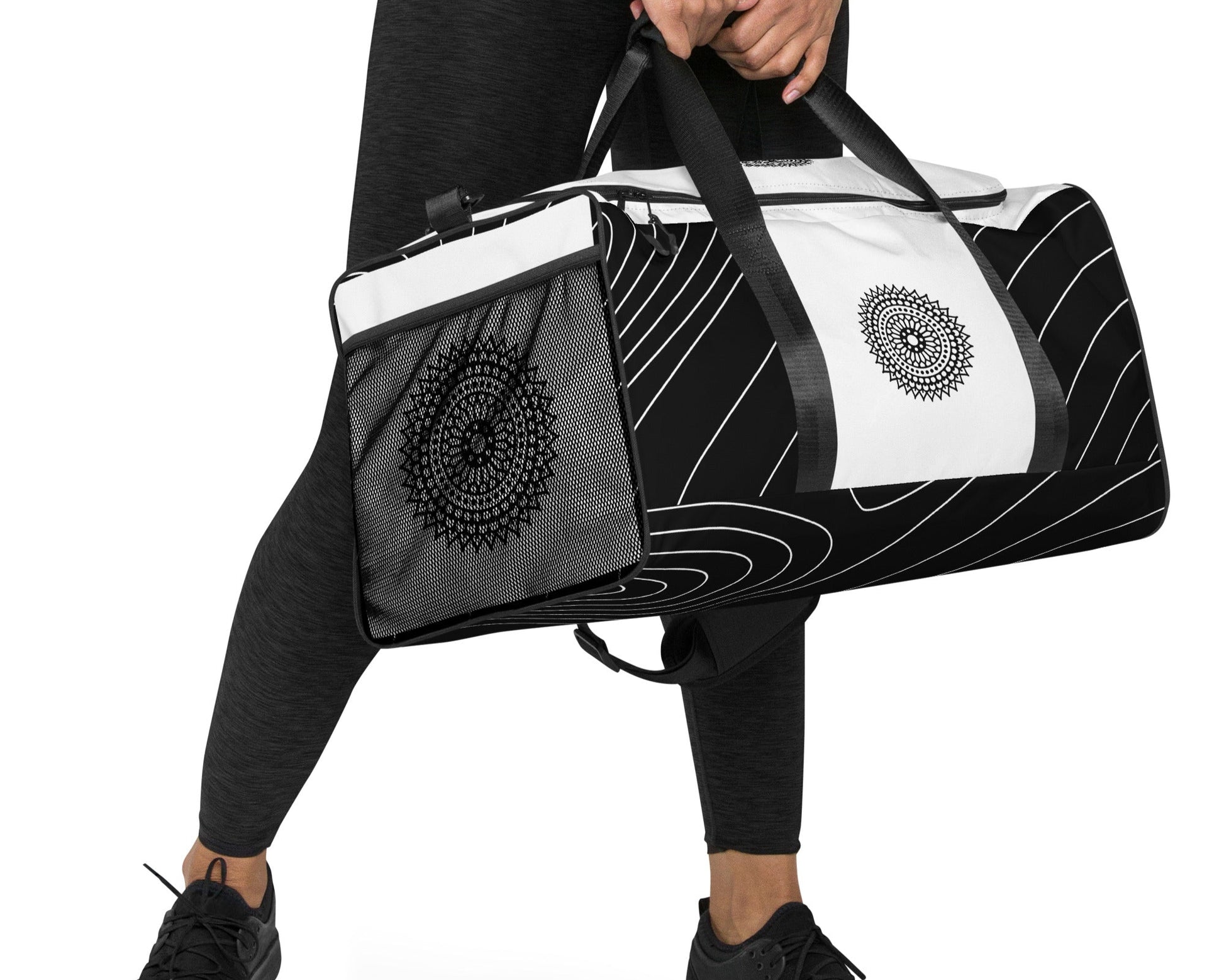 Right front of black and white print duffle bag with black mandala being carried by female