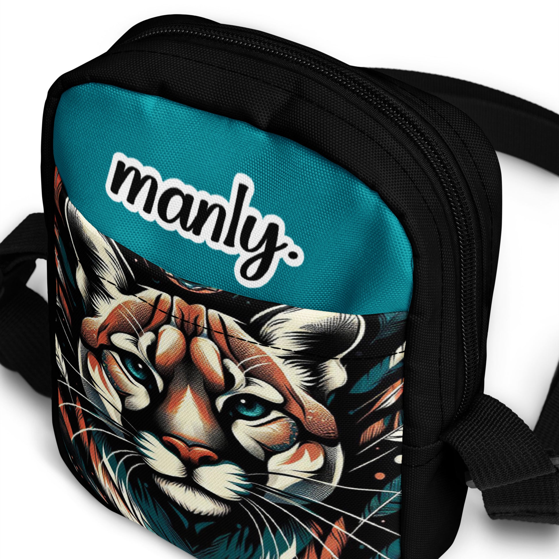 Front slanted view of Manly Cougar Utility Crossbody Bag in turquoise blue and black with head shot of a cougar and text "manly" at top