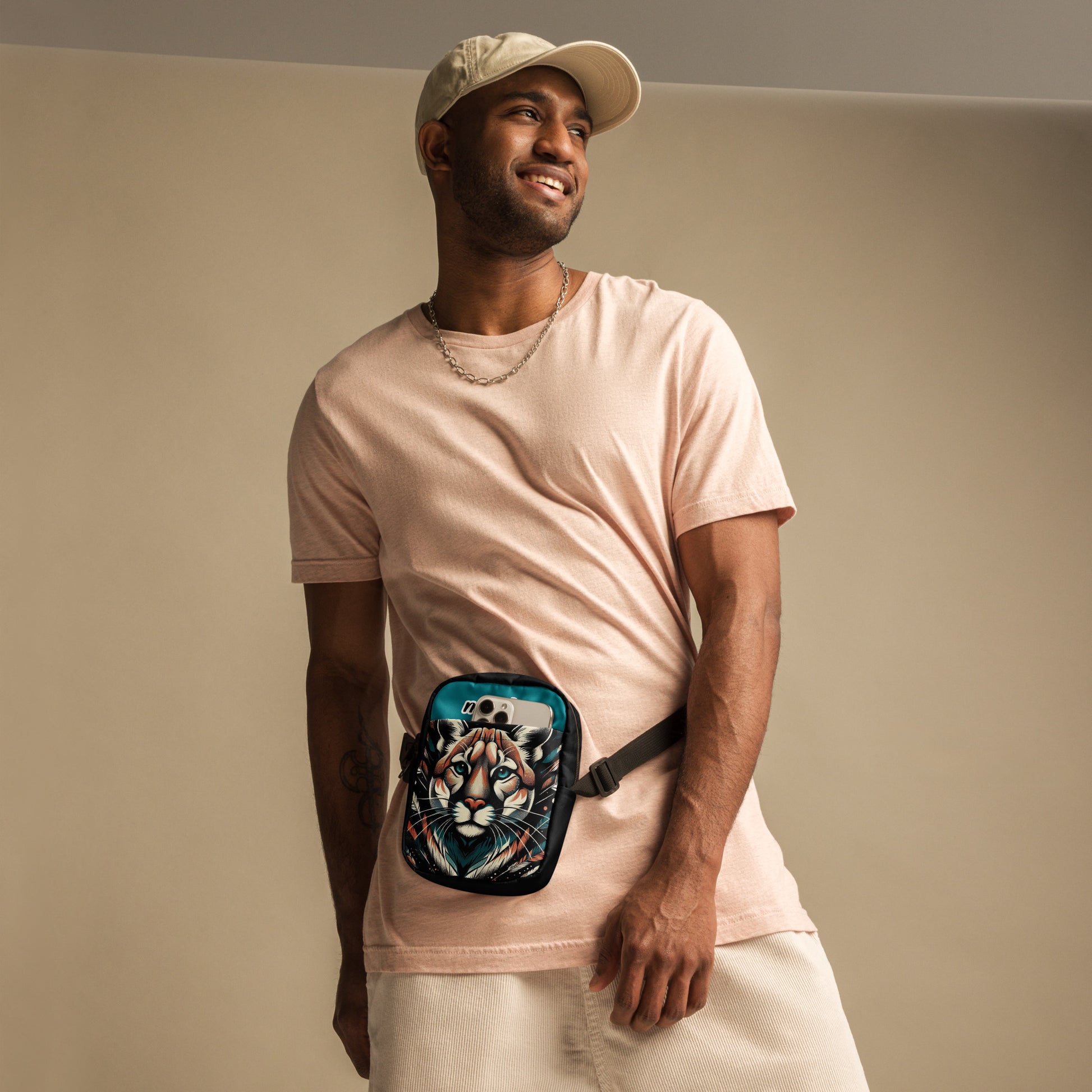 Front view of Manly Cougar Utility Crossbody Bag being worn by a male, bag in turquoise blue and black with head shot of a cougar and text "manly" at top