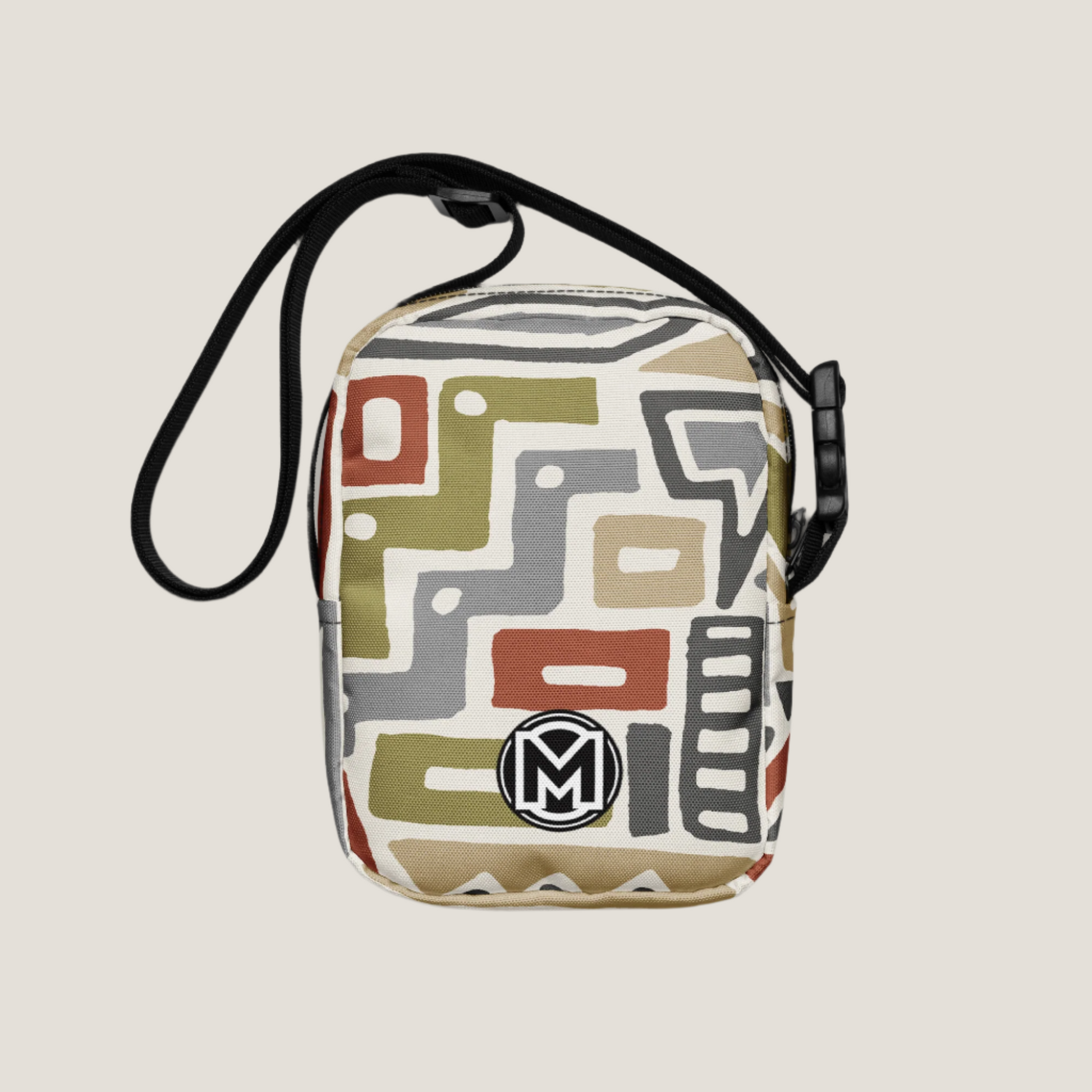 Back view of Manly Tribal Tune Utility Crossbody Bag in beige and tan print with manly logo "M" at bottom