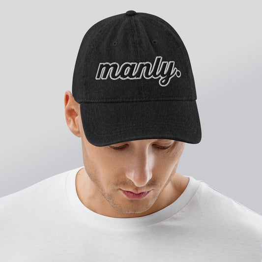 Front of black cotton hat with words 'manly' embroidered across the front