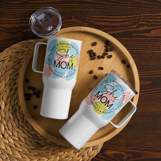 Right and left side views of a white 25 oz travel mug with black text saying 'She is mom' on a light blue, green, pink print background