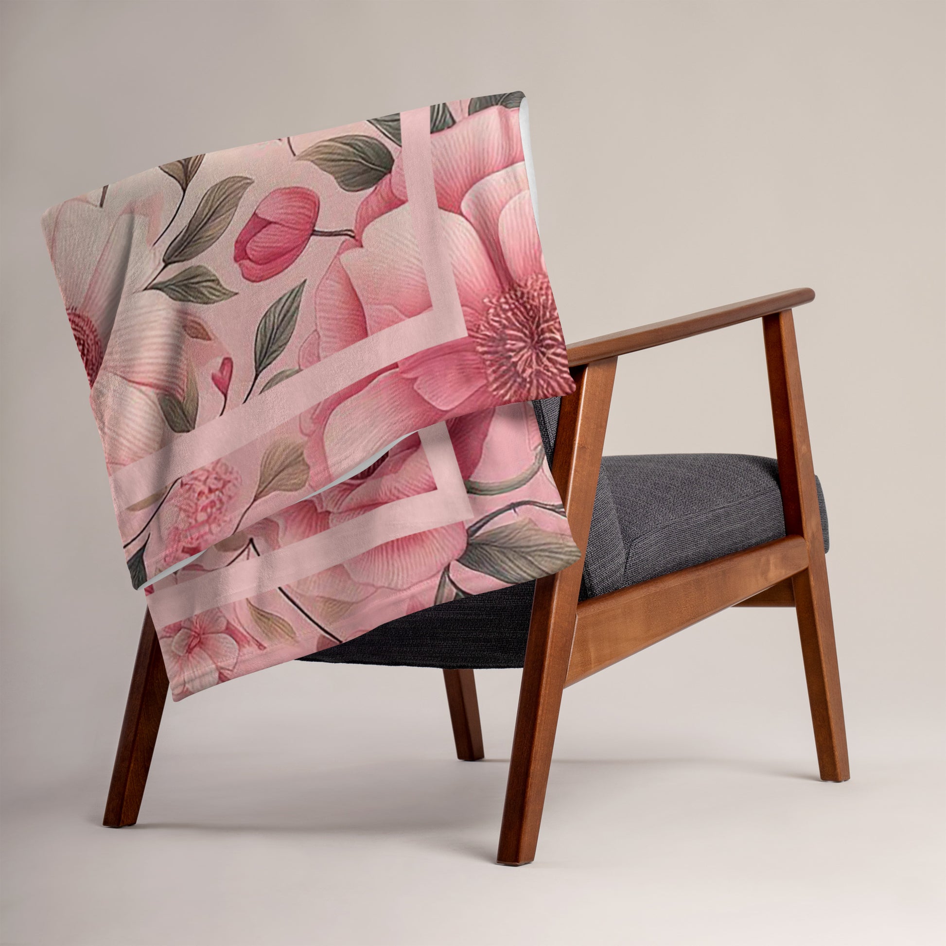 Folded Survivor floral pink 50 x 60 throw blanket draped on back of a brown chair with image of pink flowers and green leaves
