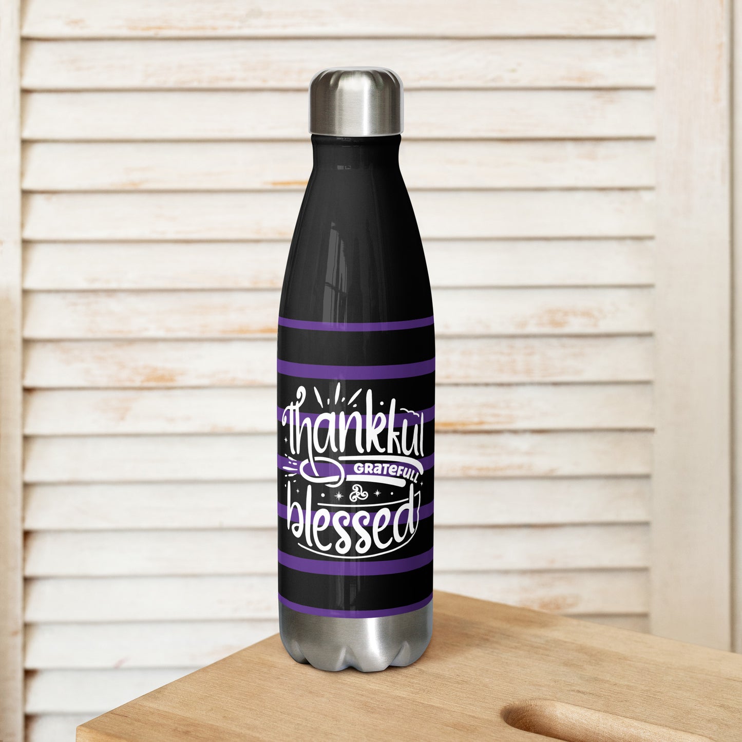 Back view of a black 17 oz stainless steel water bottle with purple and white lines and white text saying 'Thankful and blessed'