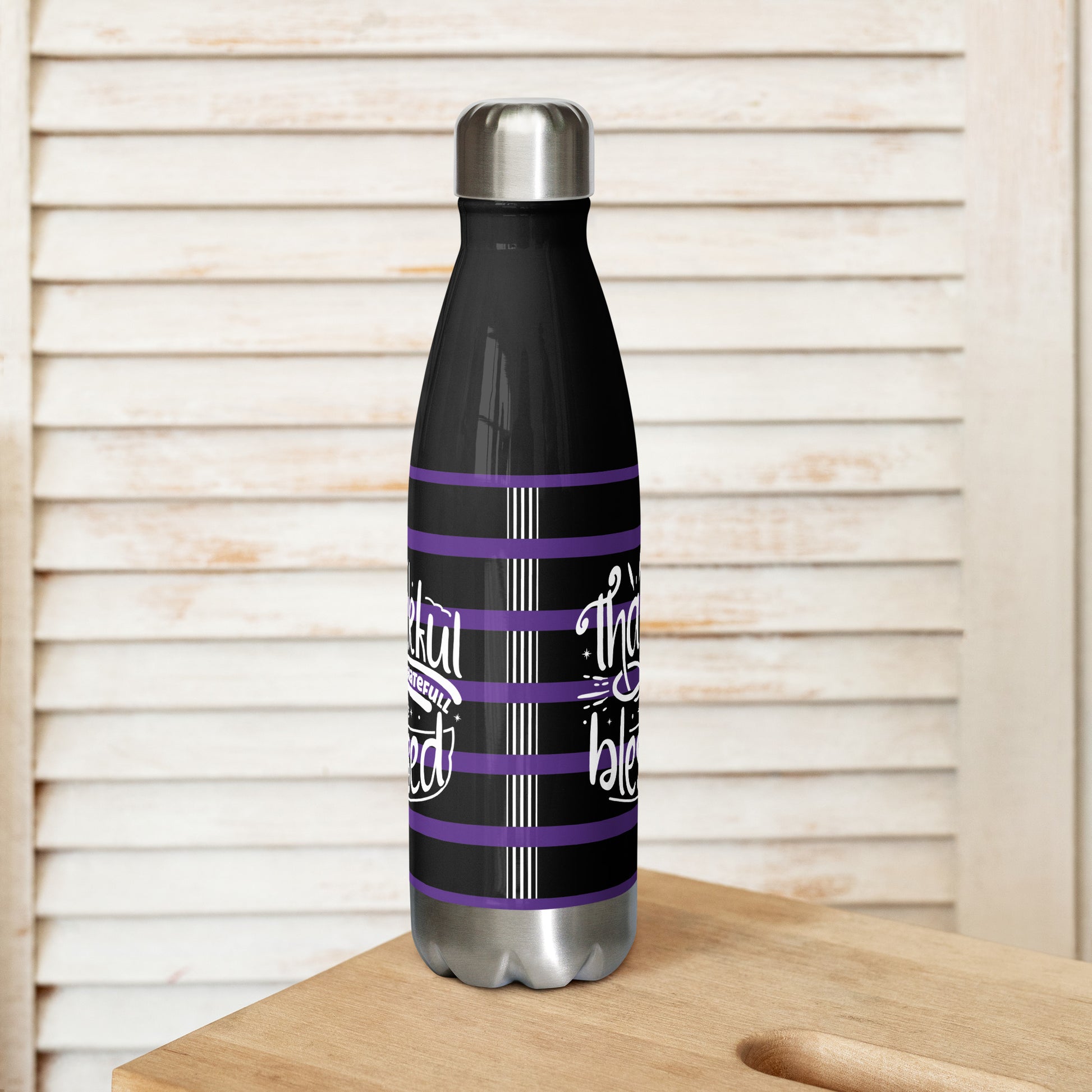 Right view of a black 17 oz stainless steel water bottle with purple and white lines and white text saying 'Thankful and blessed'